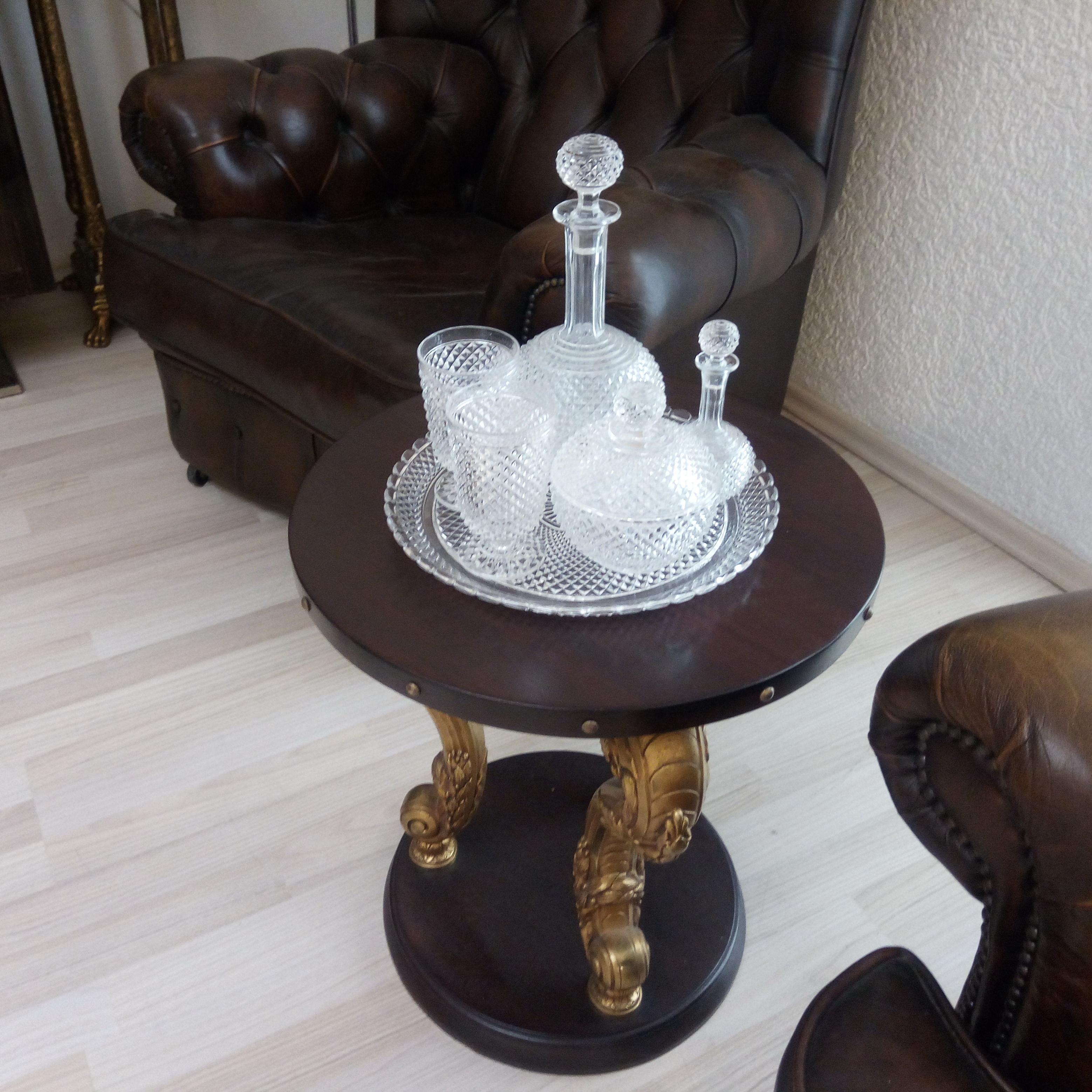 Petite table, base et plateau en bois circulaire, réunis par trois pieds en bronze doré. Deux pieds anciens en moulures métalliques courbes, d'inspiration néoclassique, contrastant avec un pied cylindrique contemporain. Autour du sommet clouté de