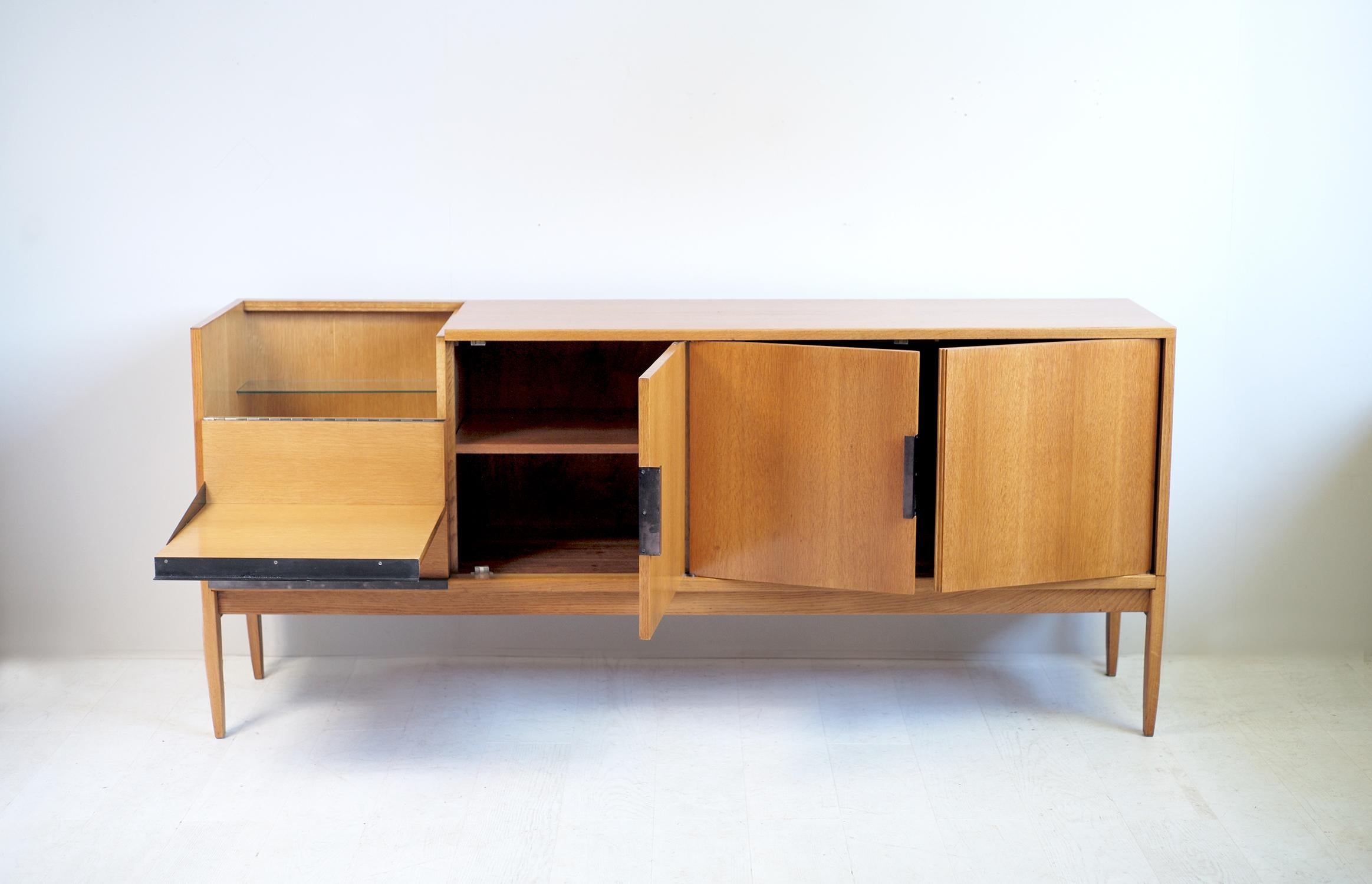 Roger Landault, Sideboard in oak, handle in blackened metal, France, 1960. The design of a beautiful sobriety combines blond oak, highlighted by handles in folded metal with gunmetal patina. The bar part opens and tilts to form a serving tray. A