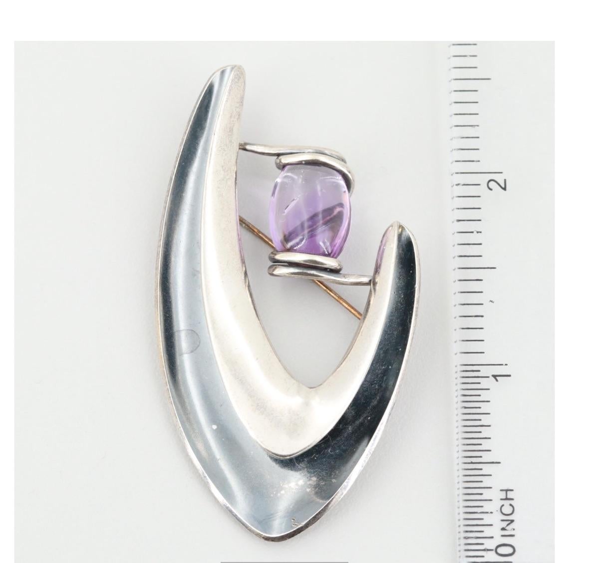 Vintage Modernist Sterling Silver Brooch by Legendary Mexico Artisan Sigi Pineda with a Large Amethyst Center Stone.
A Distinctive Refined Piece to Wear Proudly in Style.

Sigi has worked with silver many years. At age 10, Sigi began to work as an