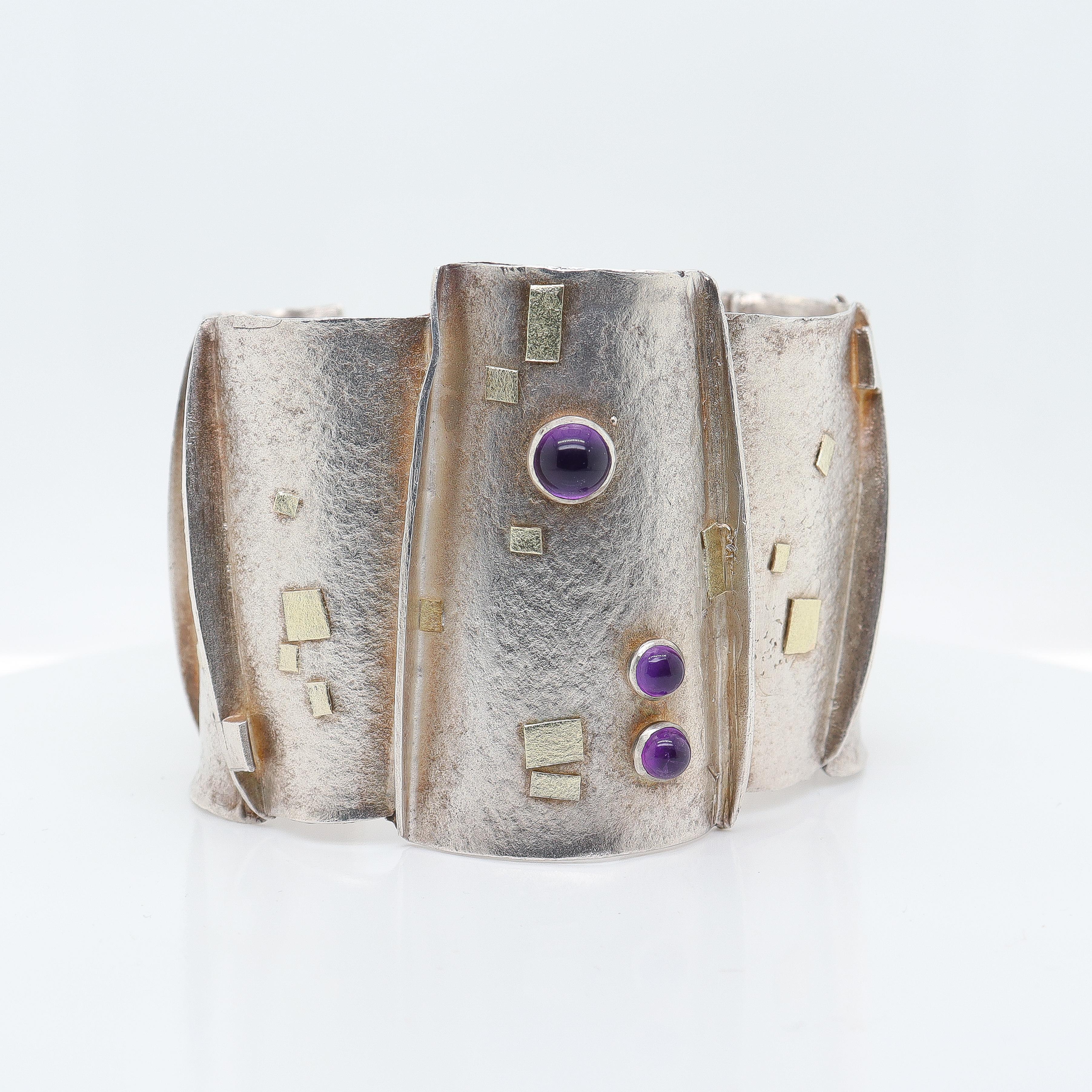 A fine vintage modernist bracelet in silver, gold and amethysts.

Constructed of 9 welded sections with a wonderful brushed finish to the front and interior, applied geometric gold elements, and bezel set amethyst cabochons.

Attributed to Enid