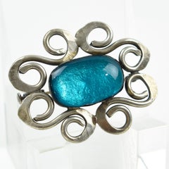 Broche moderniste en métal argenté avec cabochon en verre bleu électrique