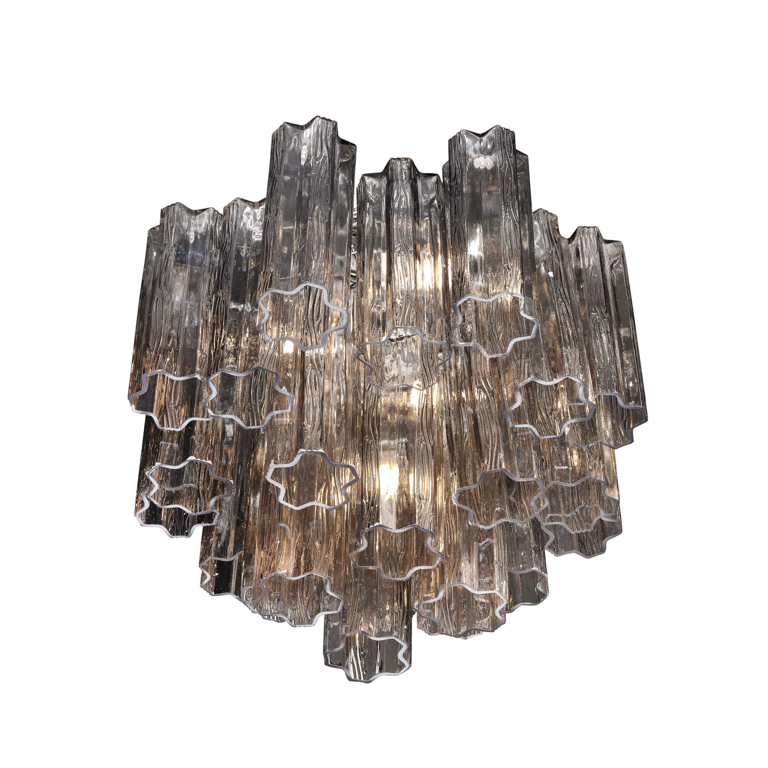 This Modernist Smoked Glass Multi-Tier Stepped Tronchi Chandelier W/Chrome Fittings originates from Italy, circa 1980. Featuring a multi-tiered stepped composition of semi translucent smoked Tronchi glass elements hanging from a chrome frame, this