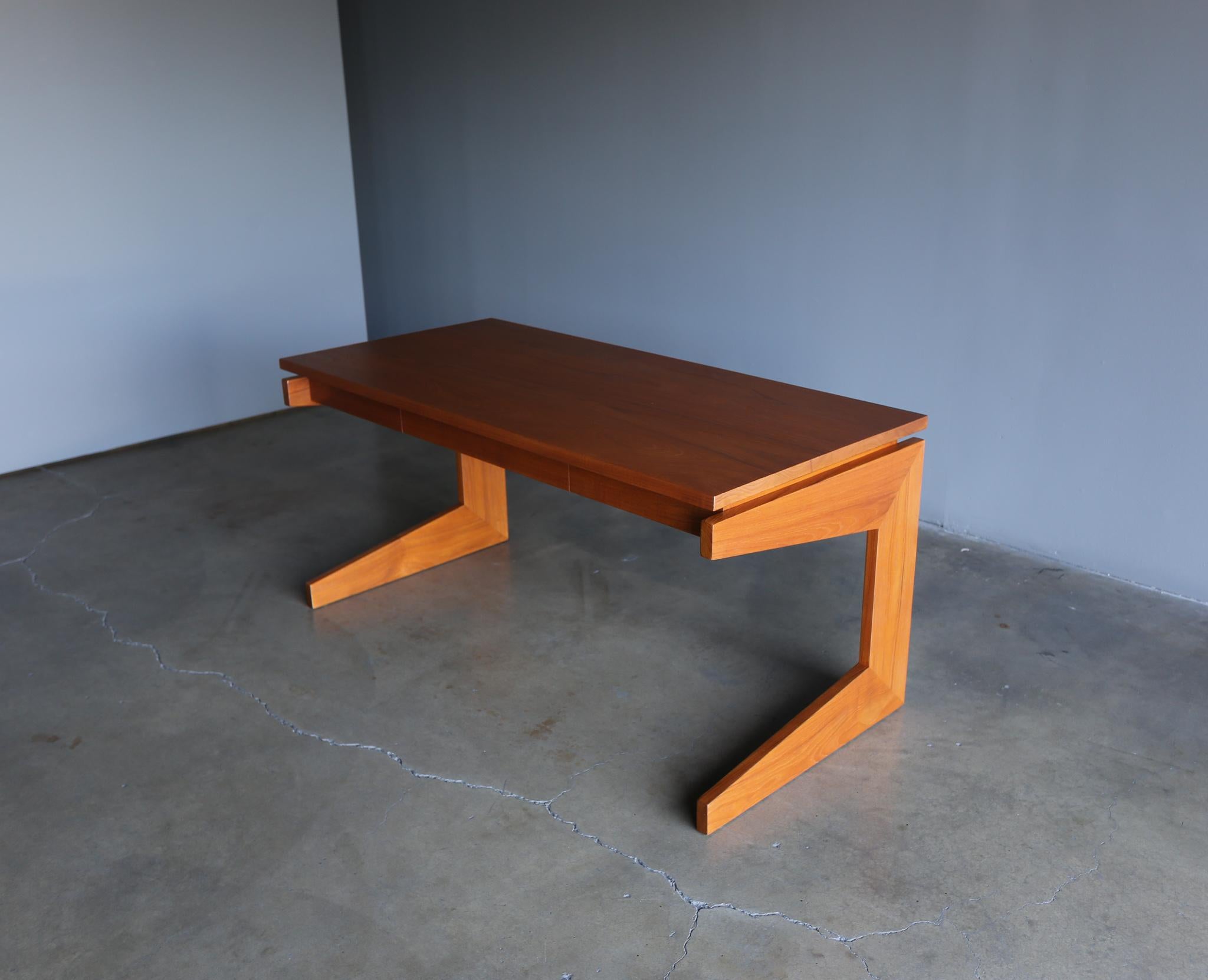 Modernist solid teak writing desk, circa 1960. This piece has been professionally restored.