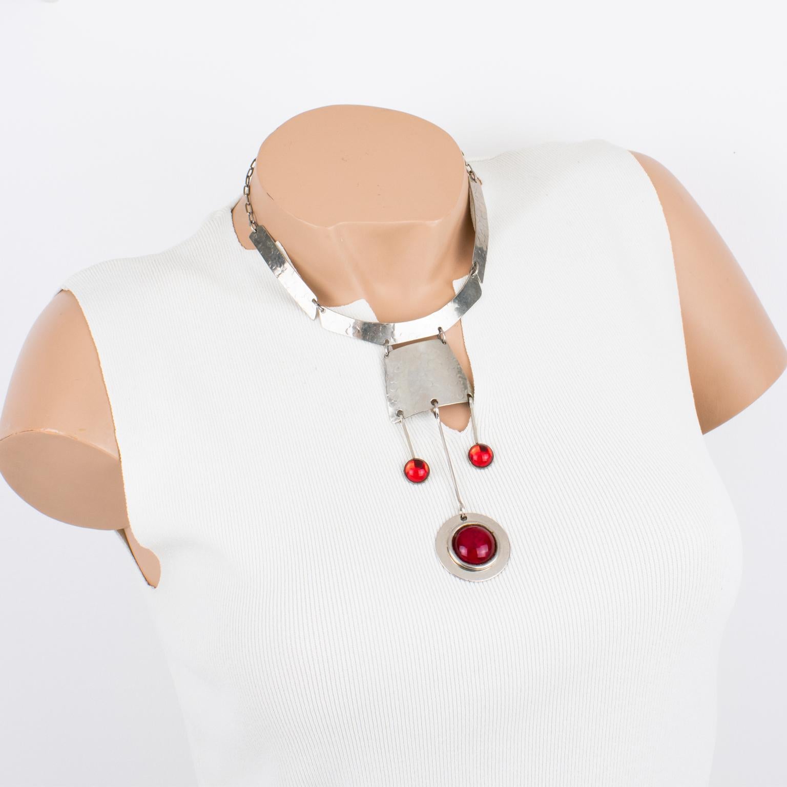 This stunning modernist Space Age necklace was crafted in France in the 1970s. The choker boasts stainless steel hammered geometric elements ornate with dangling charm pendants. The decorative charm pendants are embellished with bright red glass