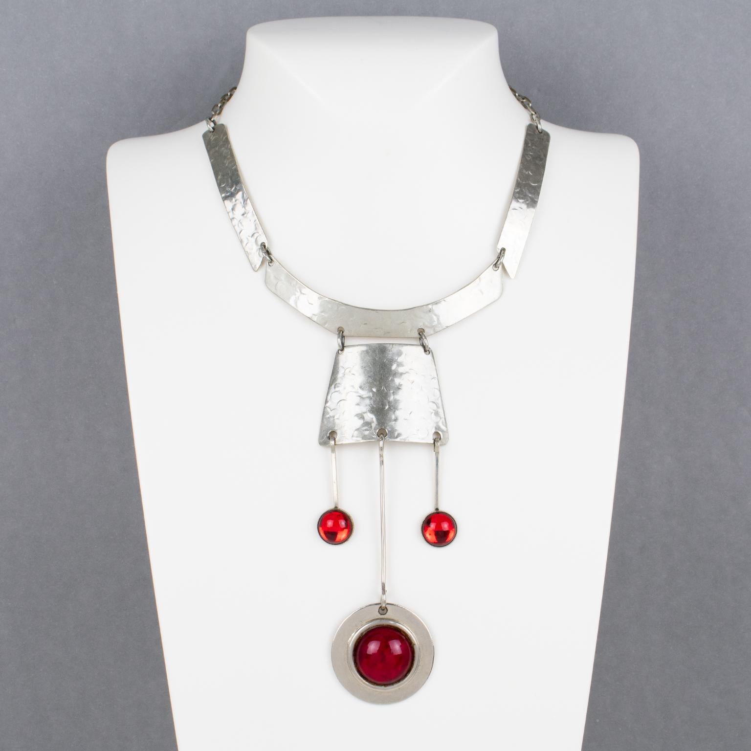 This stunning modernist Space Age necklace was crafted in France in the 1970s. The choker boasts stainless steel hammered geometric elements, ornate with dangling charm pendants. The decorative charm pendants are embellished with bright red glass