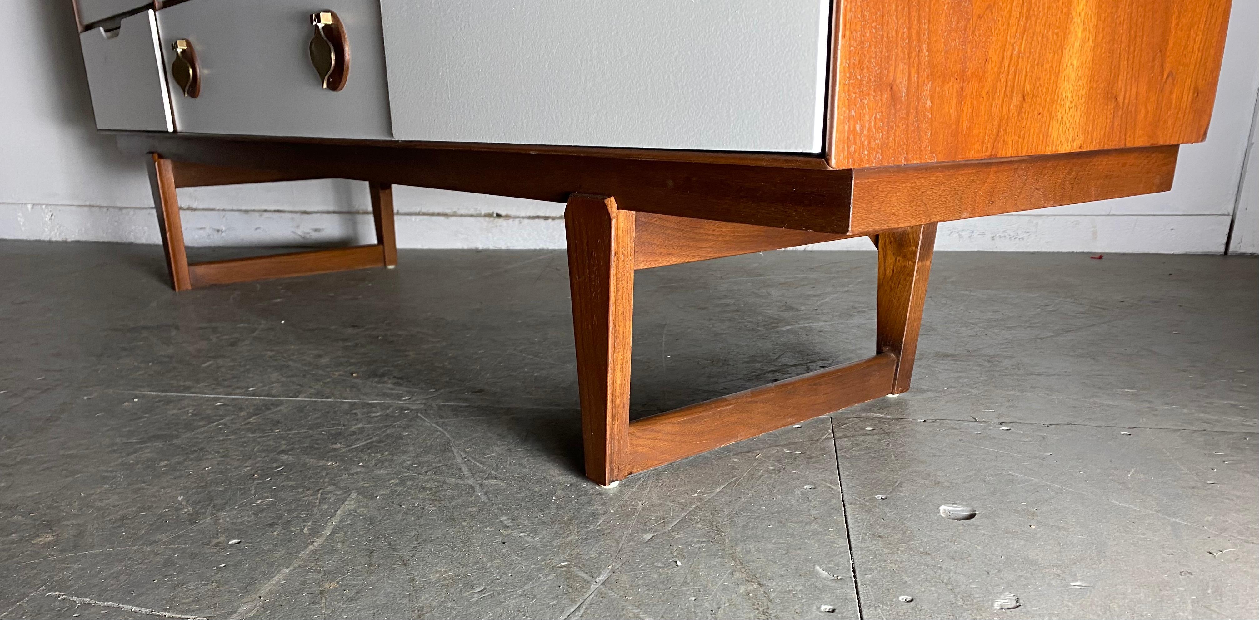 Elegant Mid-Century Modern furniture by Stanley featuring white front drawers accenting the deep figured walnut wood body. Spacious drawers with over-sized brass spade shaped hardware that add a whimsical style. Unusual sled leg design. Superior