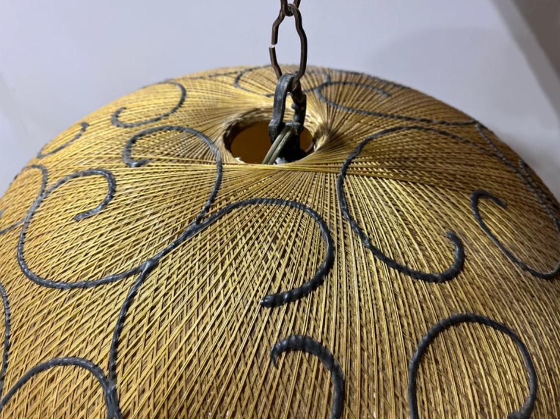 Modernist Spanish rattan hanging light pendant with a ball shaped shade. 

The design showcases a meticulously crafted woven rattan shade, elegantly accented with black detailing to evoke a refined modernist aesthetic. Suspended from distinctive