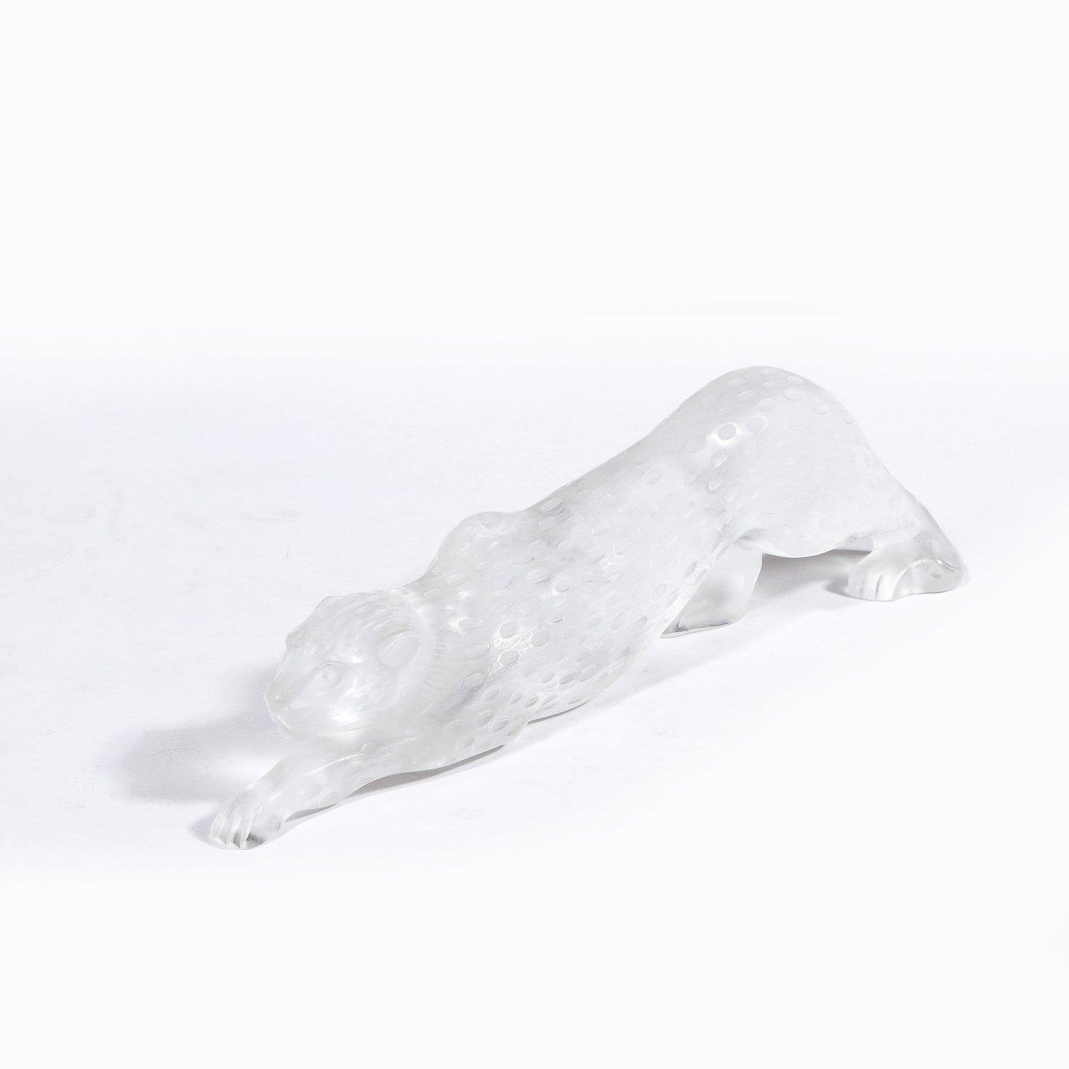 Este elegante leopardo modernista de cristal esmerilado fue realizado en Francia por el legendario fabricante Lalique, hacia 1980. Representa a una pantera cazadora, arrastrándose a cuatro patas por el suelo, aparentemente en pleno acecho de su