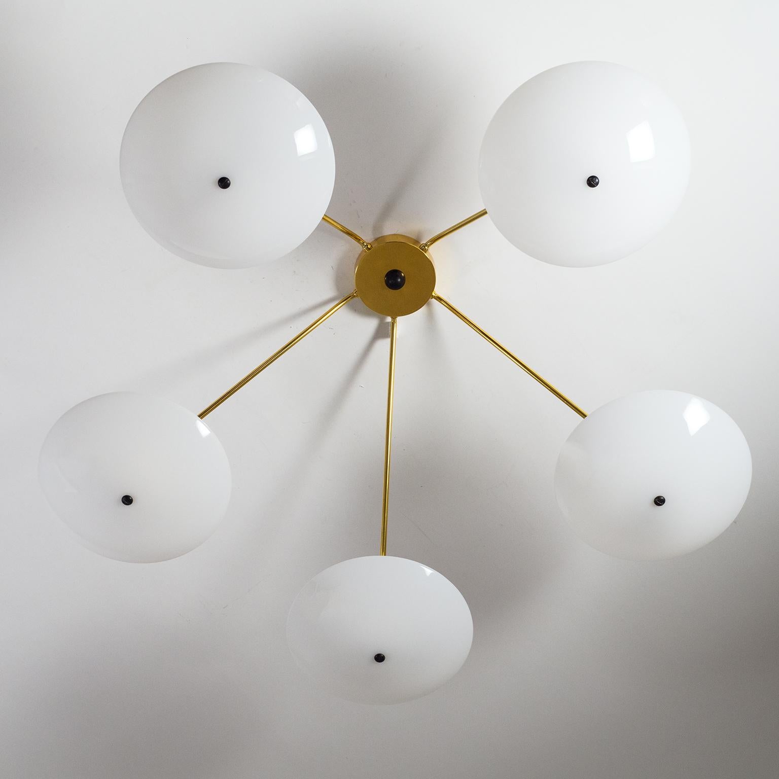 Brilliant modernist ceiling light from the 1950s. Five brass arms in varying lengths, each with an opaque acrylic diffuser, are mounted slightly asymmetrically on a minimalist brass ceiling unit. Despite their different lengths, the arms are angled