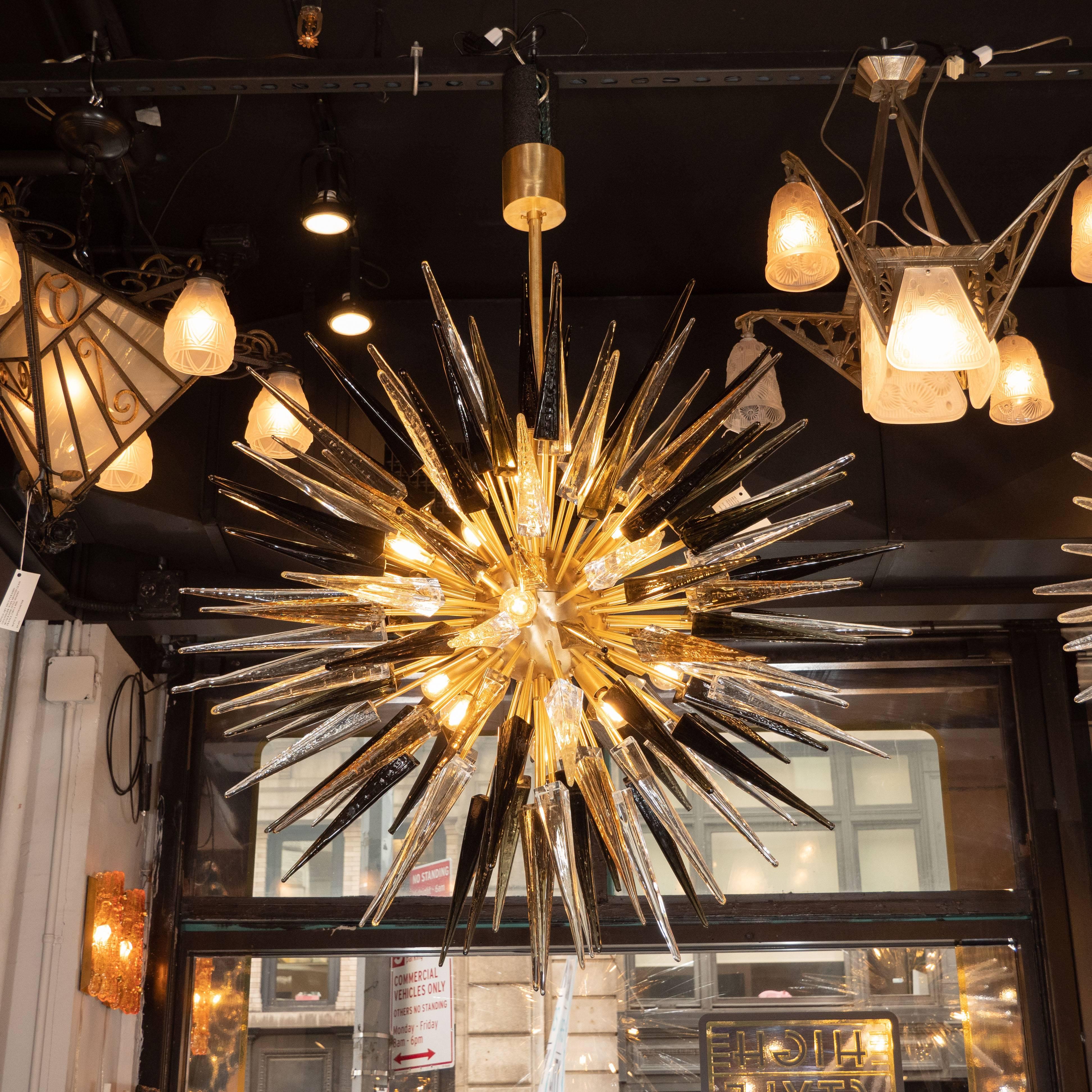 This stunning and graphic modernist chandelier was realized in Murano, Italy- the islands off the coast of Venice renowned for centuries for their superlative quality glass. It features an abundance of hand blown Murano glass obelisks in