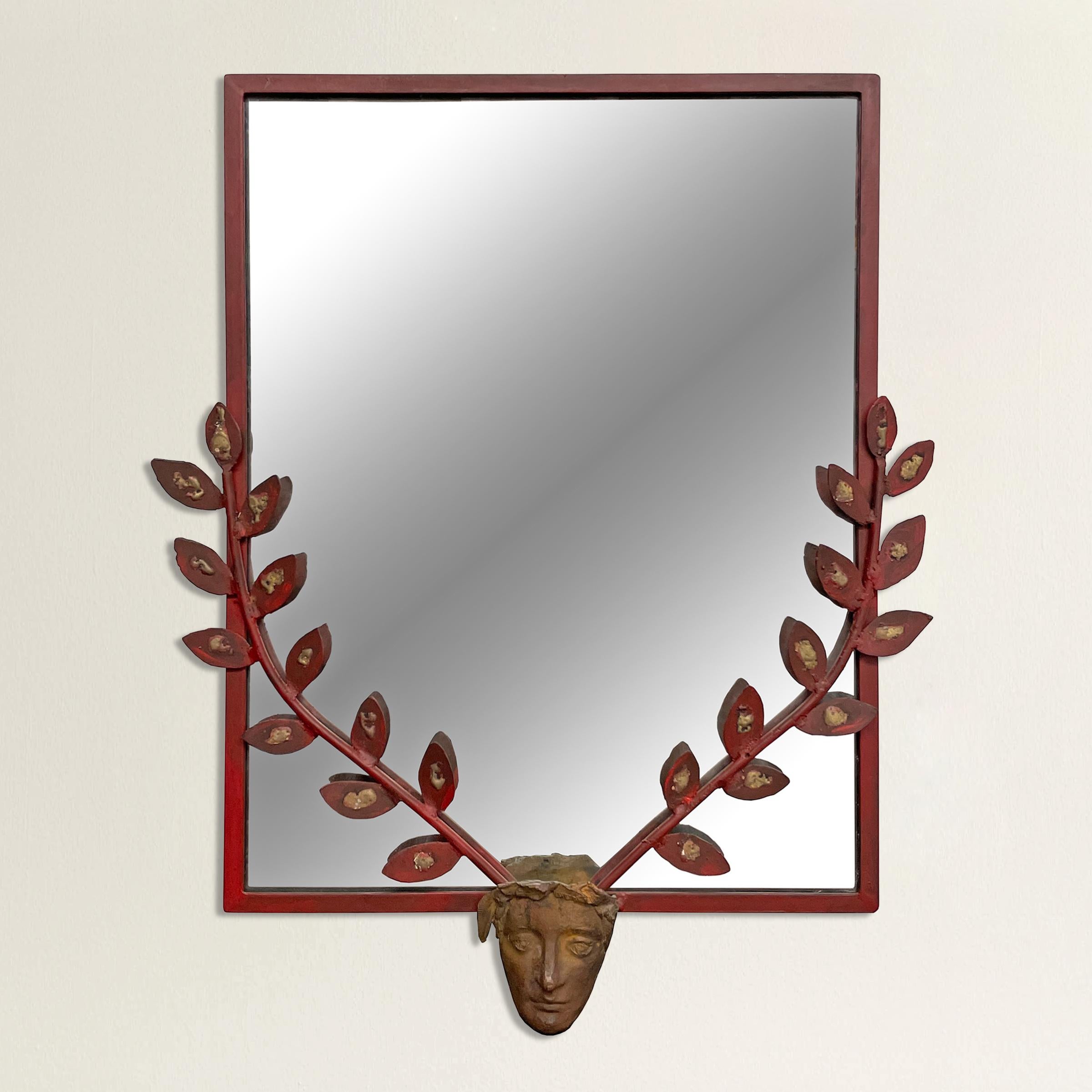 An incredible mid-20th century French red painted steel framed mirror with a cast bronze face with two laurel leaf branches, with a bronze drip in the center of each leaf.