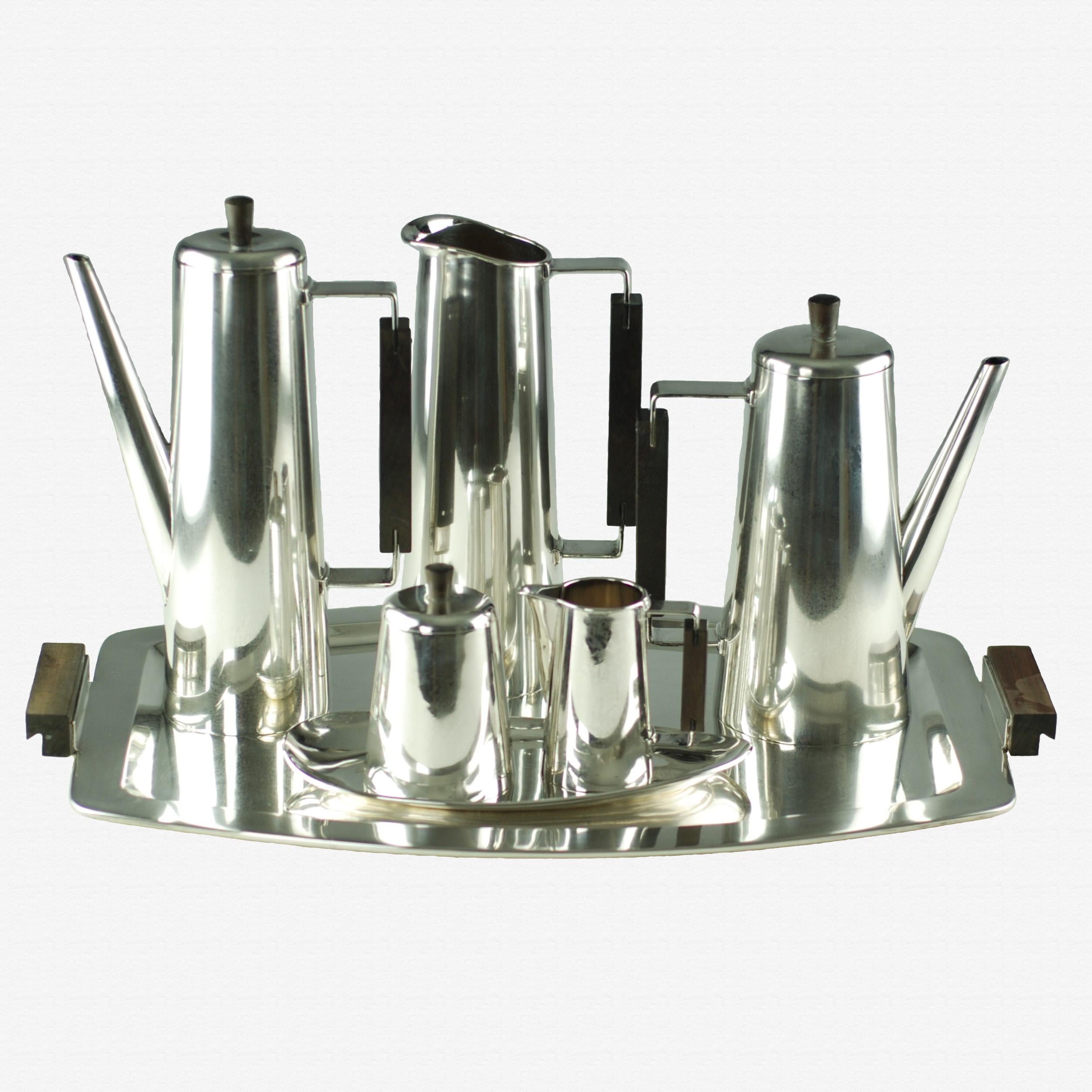 This elegant matched seven-piece Modernist coffee or tea set is made of sterling silver and rosewood. The set includes a coffee pot, tea pot, pitcher, cream jug and covered sugar bowl. The cream and covered sugar bowl come complete with their own