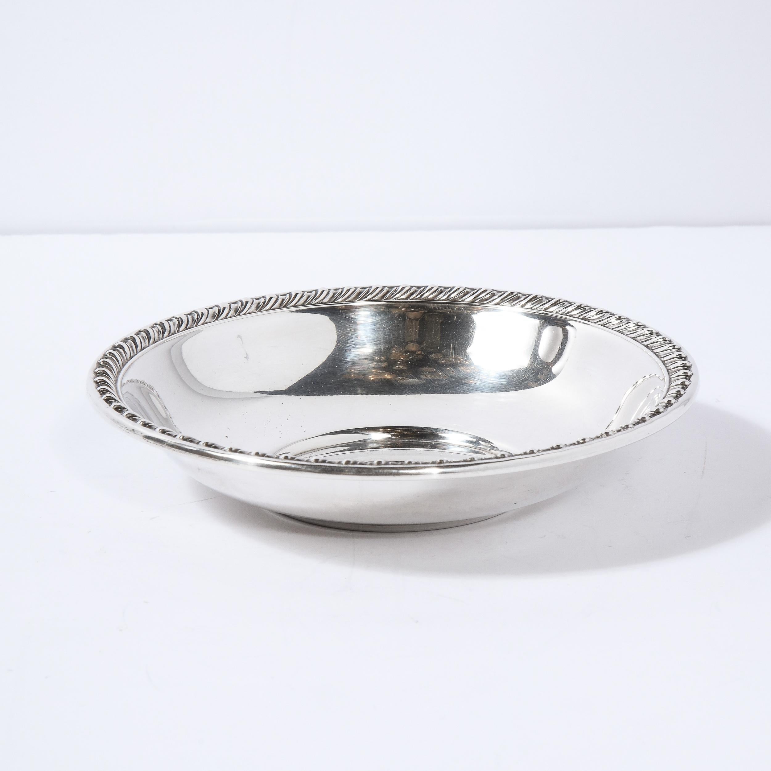 This elegant sterling silver dish was realized in the United States. It features an austere concave form with angled sides and a beaded border. With its clean modernist lines and beautiful quality, this piece would be a winning addition to any style