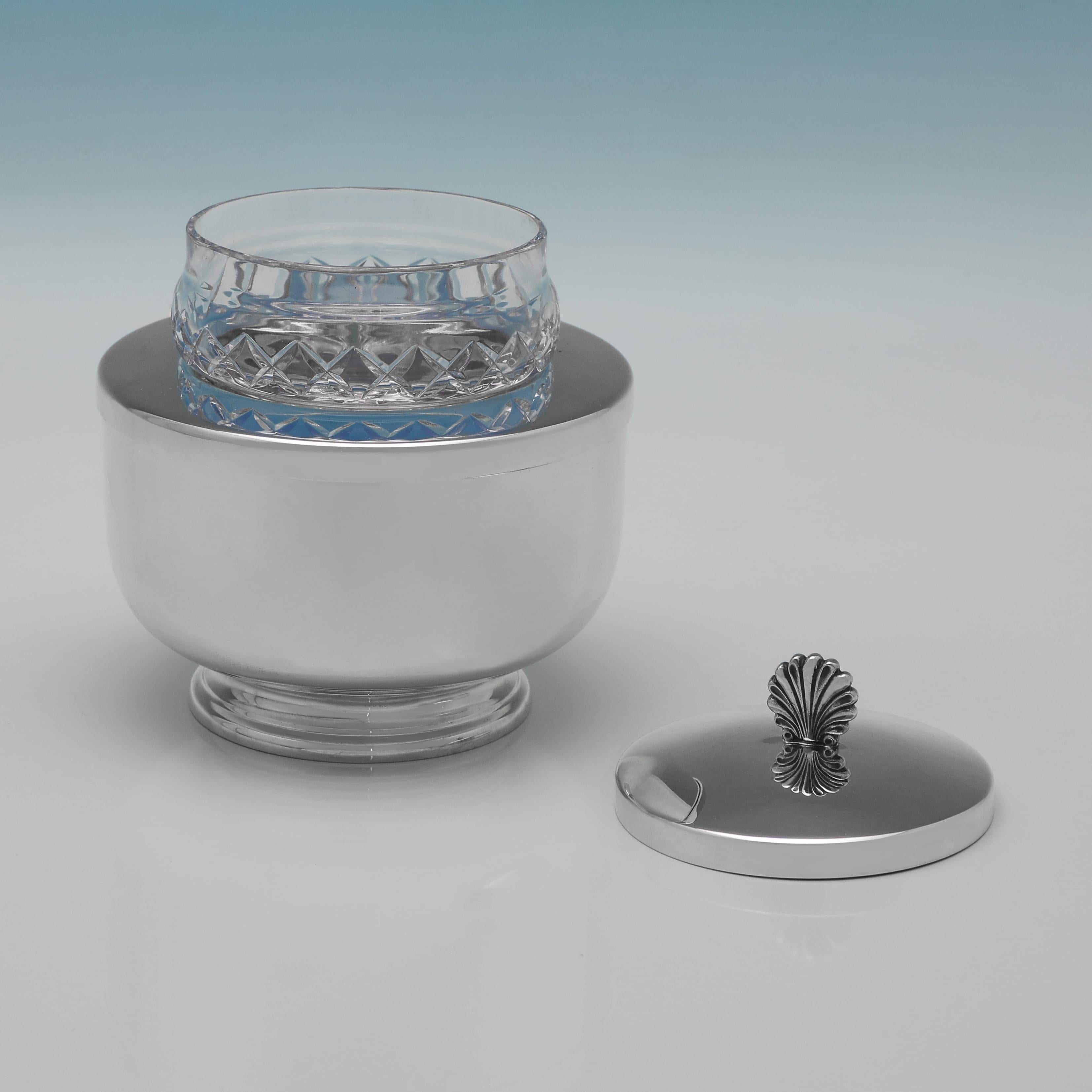 Poinçonné à Londres en 1996 par Asprey & Co. Ltd, ce plat à caviar raffiné en argent sterling et en verre taillé présente un corps poli simple avec une doublure en verre insérée, surmonté d'un couvercle en argent surmonté d'un fleuron en coquillage