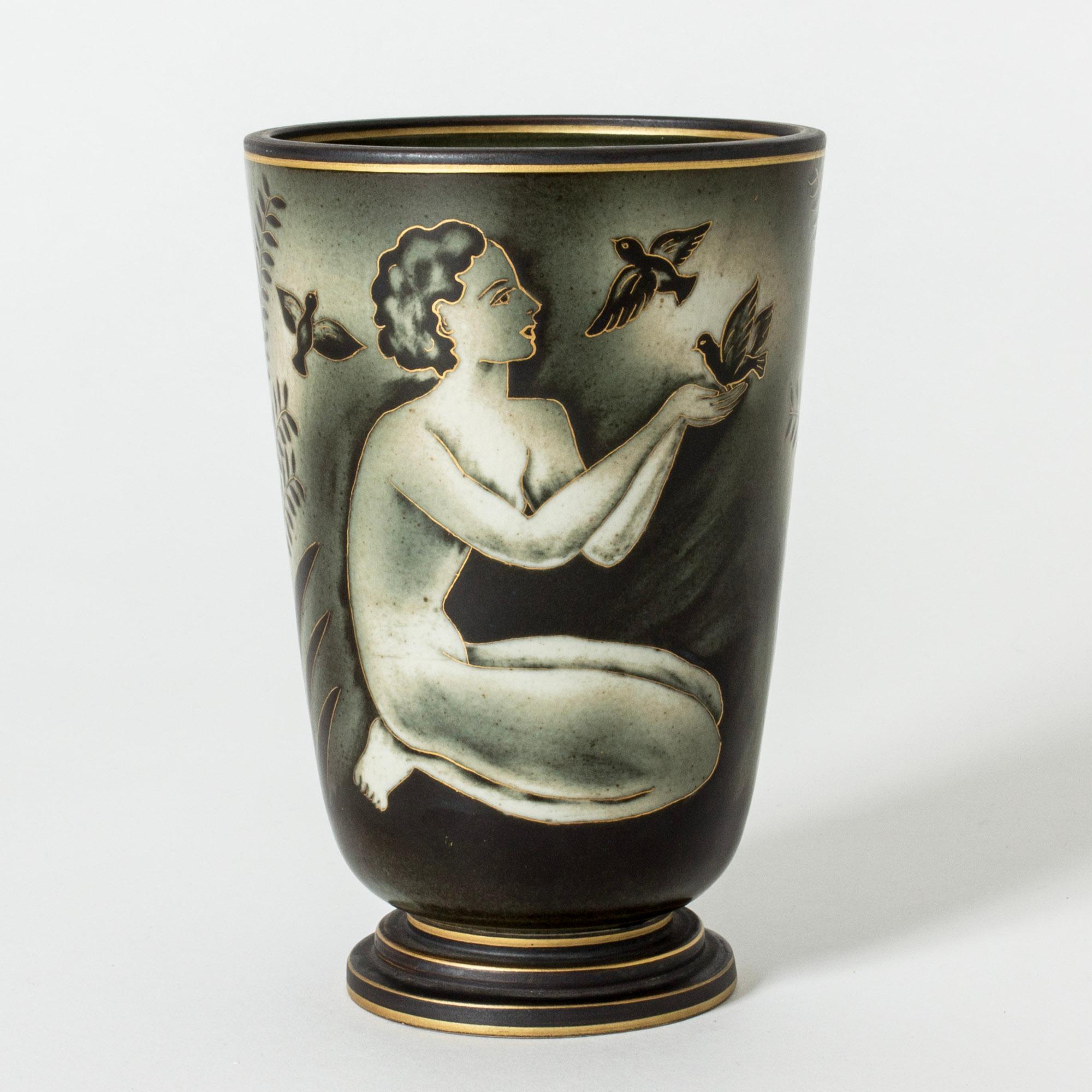 Lovely stoneware vase by Gunnar Nylund, from the “Flambé” series. Beautiful decor of women among leaves and birds. Gold decor accentuates the women’s features as well as the top and base of the vase.

Gunnar Nylund was one of the most influential