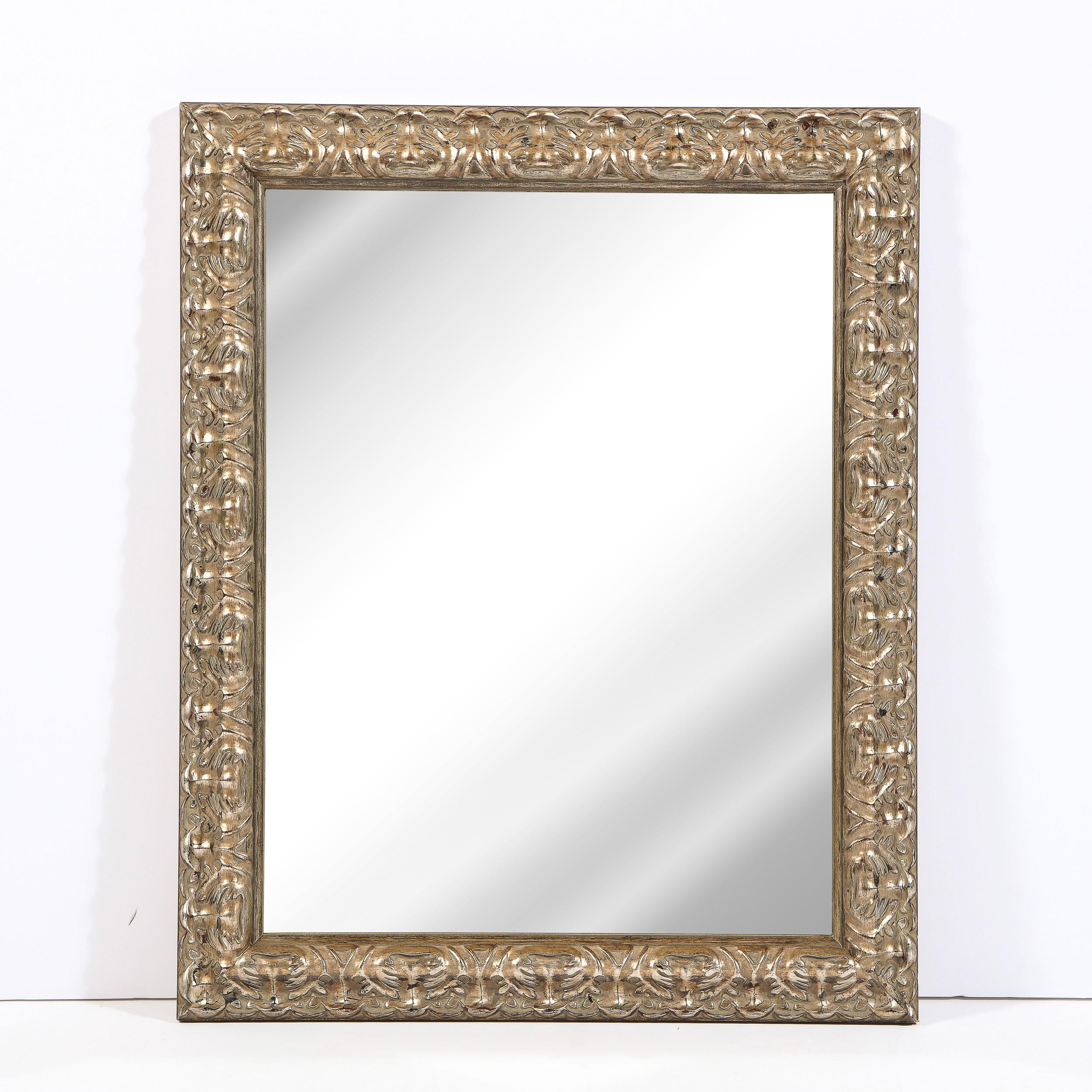 This beautiful modernist mirror was realized in the United States during the 20th century. It features a rectangular frame in giltwood with a wealth of carved abstract stylized foliate designs with a plain mirror center. With its sophisticated