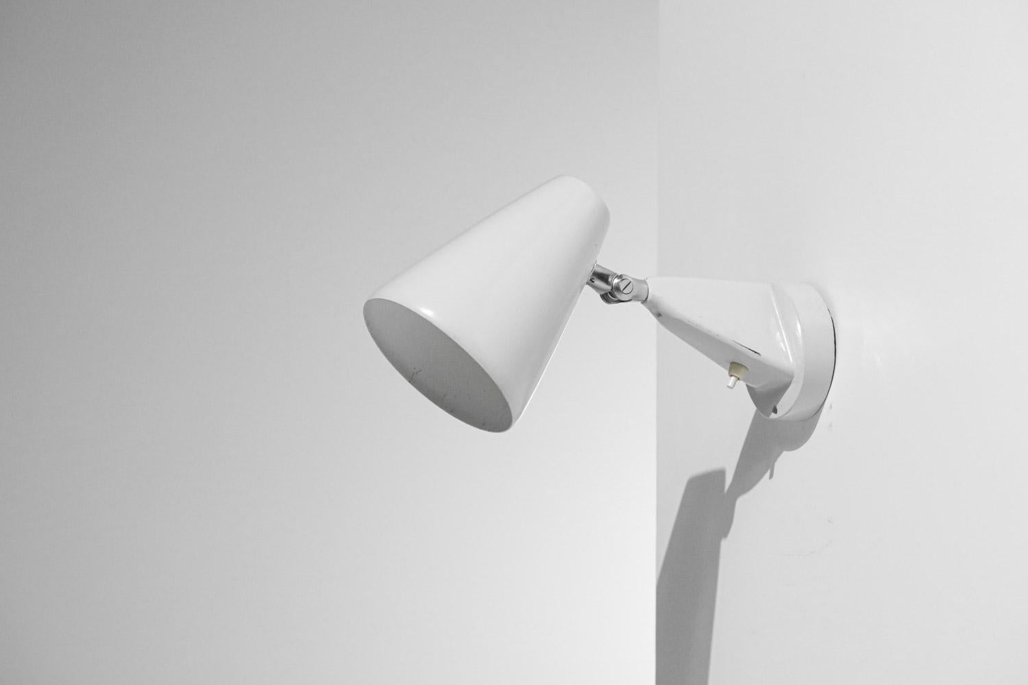 Lampada da parete scandinava in stile modernista degli anni '60 e '70. Struttura e paralume in metallo laccato bianco (vernice originale). Sistema che permette di orientare il paralume in diverse posizioni. Lampadina LED consigliata di tipo E27,