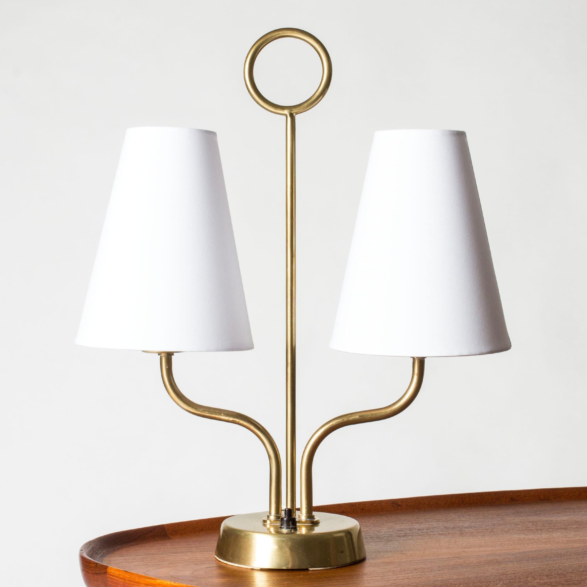Lovely table lamp by Hans Bergström with two shades, model #20. Made from brass with a hoop-shaped detail and elegant curved lines.

Hans Bergström was the owner and creative director of the lighting firm Ateljé Lyktan, which he founded in Åhus in