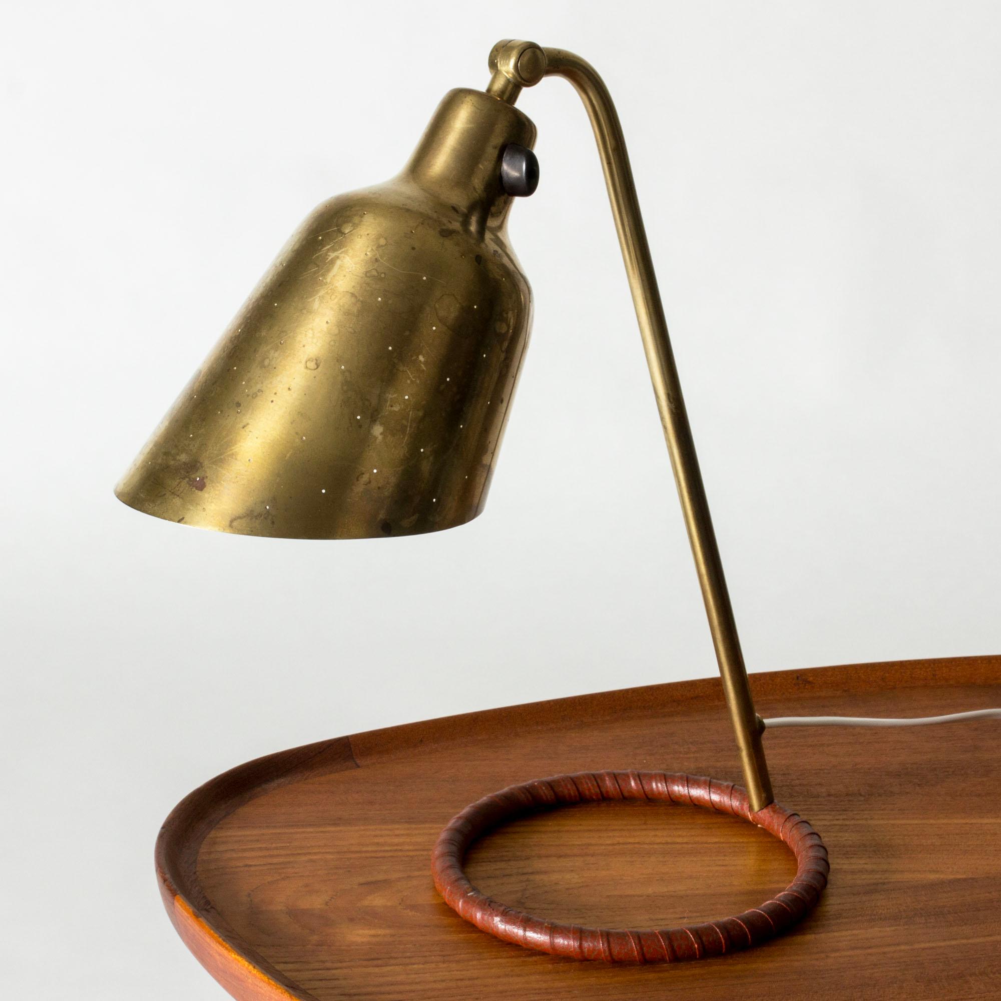 Rare desk lamp by Hans Bergström. Made from brass with a hoop-shaped base dressed with brown leather. Brass shade perforated with small holes that let out the light beautifully.

Hans Bergström was the owner and creative director of the lighting