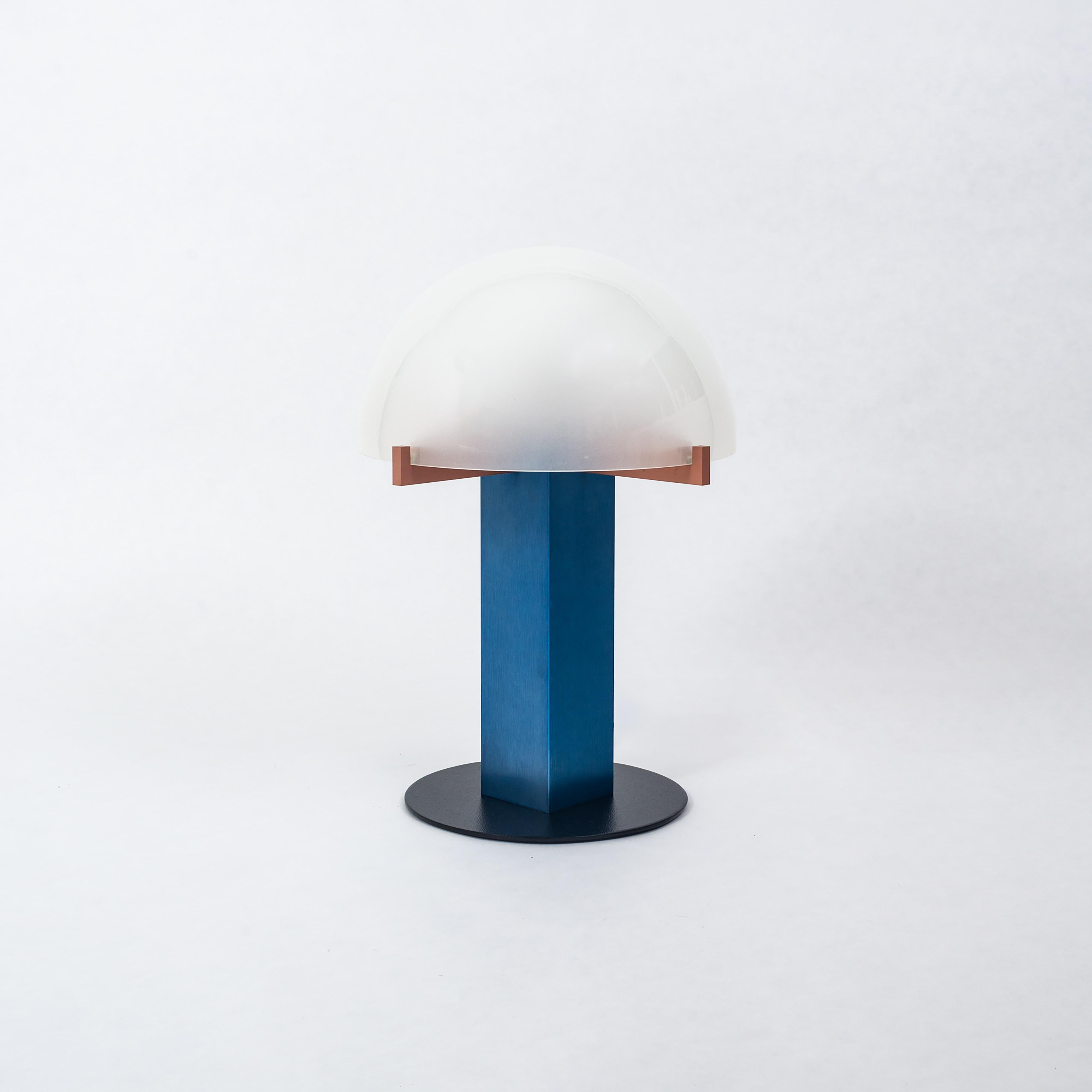 Une lampe de table moderne de Ron Rezek, vers les années 1980. Également connu sous le nom de « Lampe de chambre à coucher ». Cette lampe est composée d'aluminium brossé anodisé bleu et rouge avec un lourd abat-jour en forme de dôme en verre dépoli