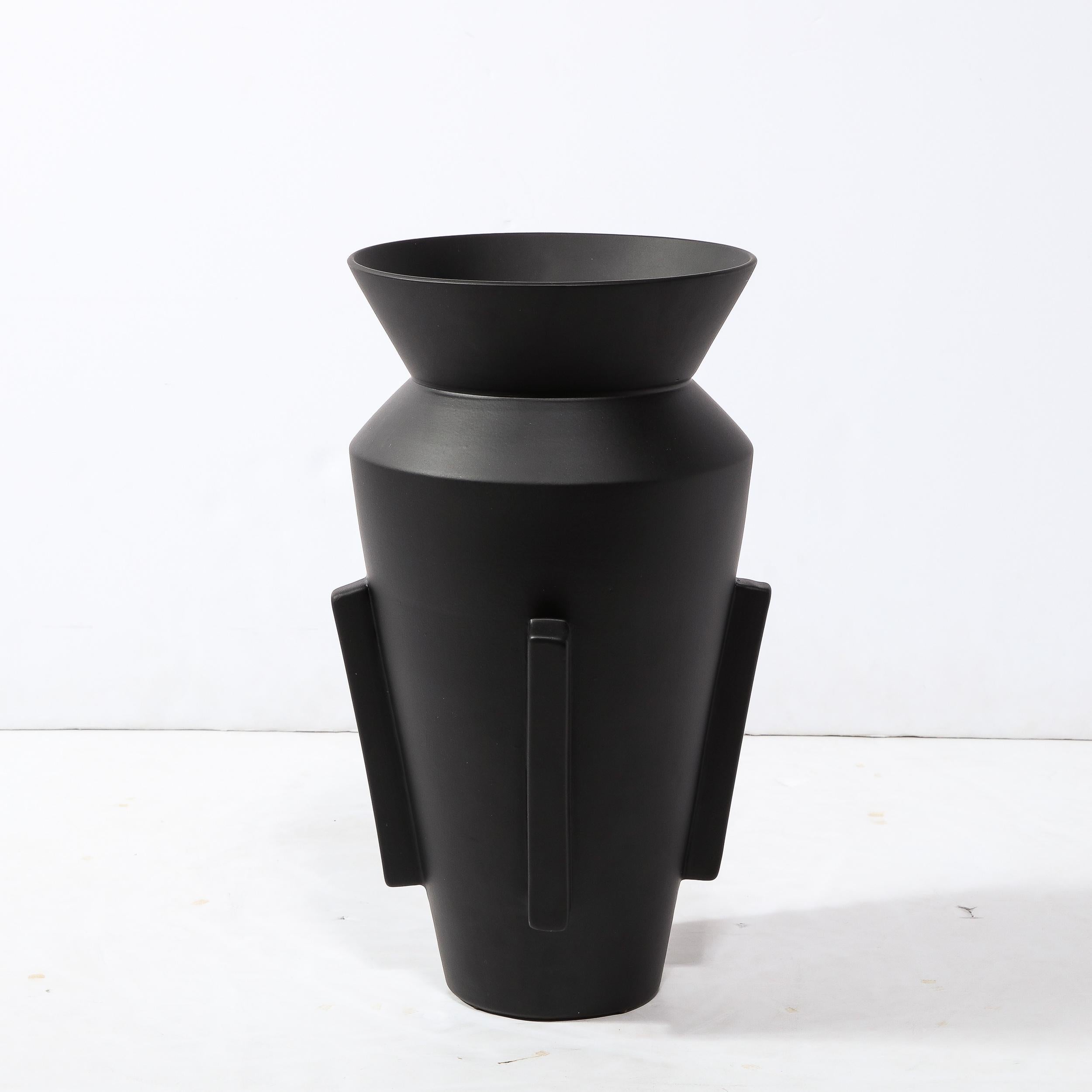 This refined and sophisticated modernist urn form vase was realized in the United States during the latter half of the 20th century. It features a conical body that flares to an hourglass collar and circular mouth. The sides of the piece offer