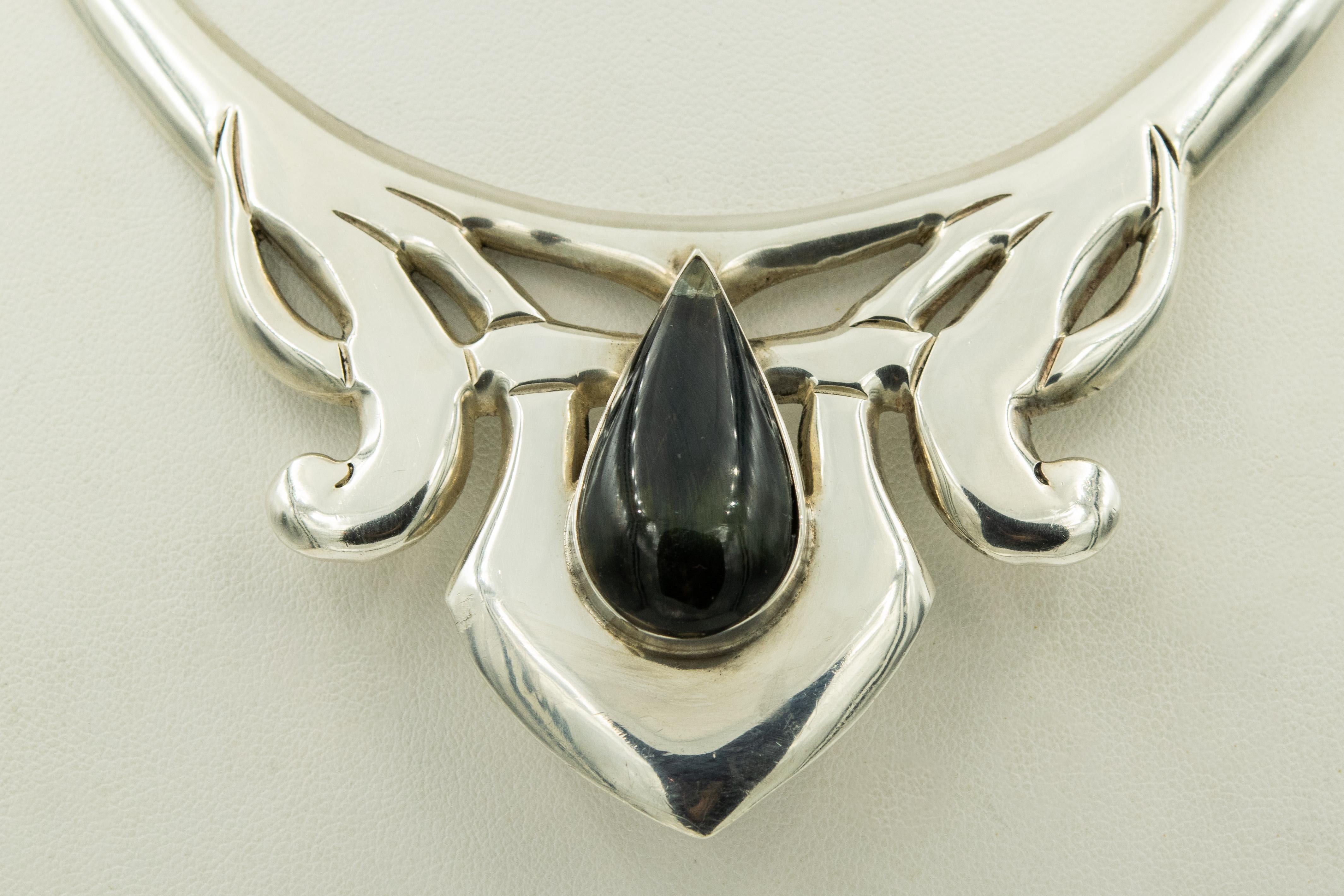 This stunning necklace has a modernist design in the center with a pear shaped rainbow obsidian in the center.  It is hinged on both sides and closes with a push in clasp at the back. The collar's inside measurement is approximately 14.5
