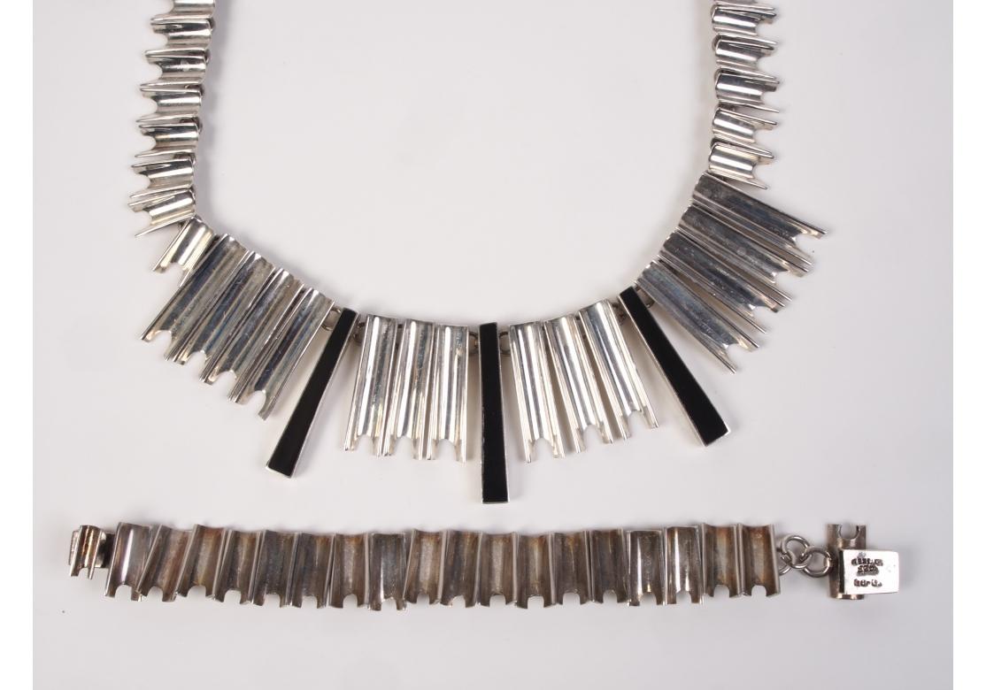 The necklace with graduated curved elements and three long black enameled bars in the center. The bracelet made up of the same type of curved sterling elements. Marked on lock, 