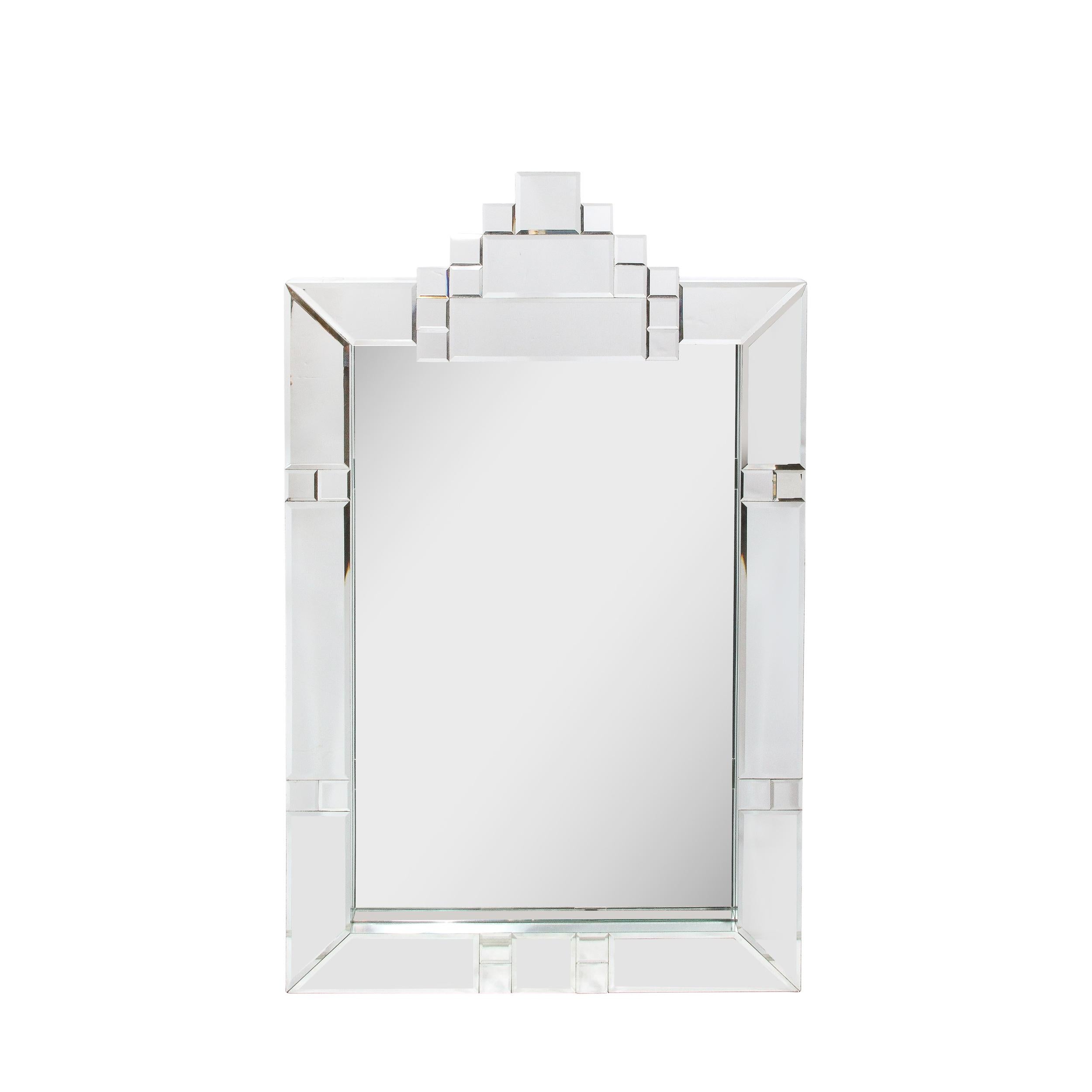 This modernist Art Deco style geometric mirror was realized in the United States circa 1970. It features a tessellated border consisting of rectangular segments of plain mirror interrupted by rows of adjacent square forms. The top of the mirror is