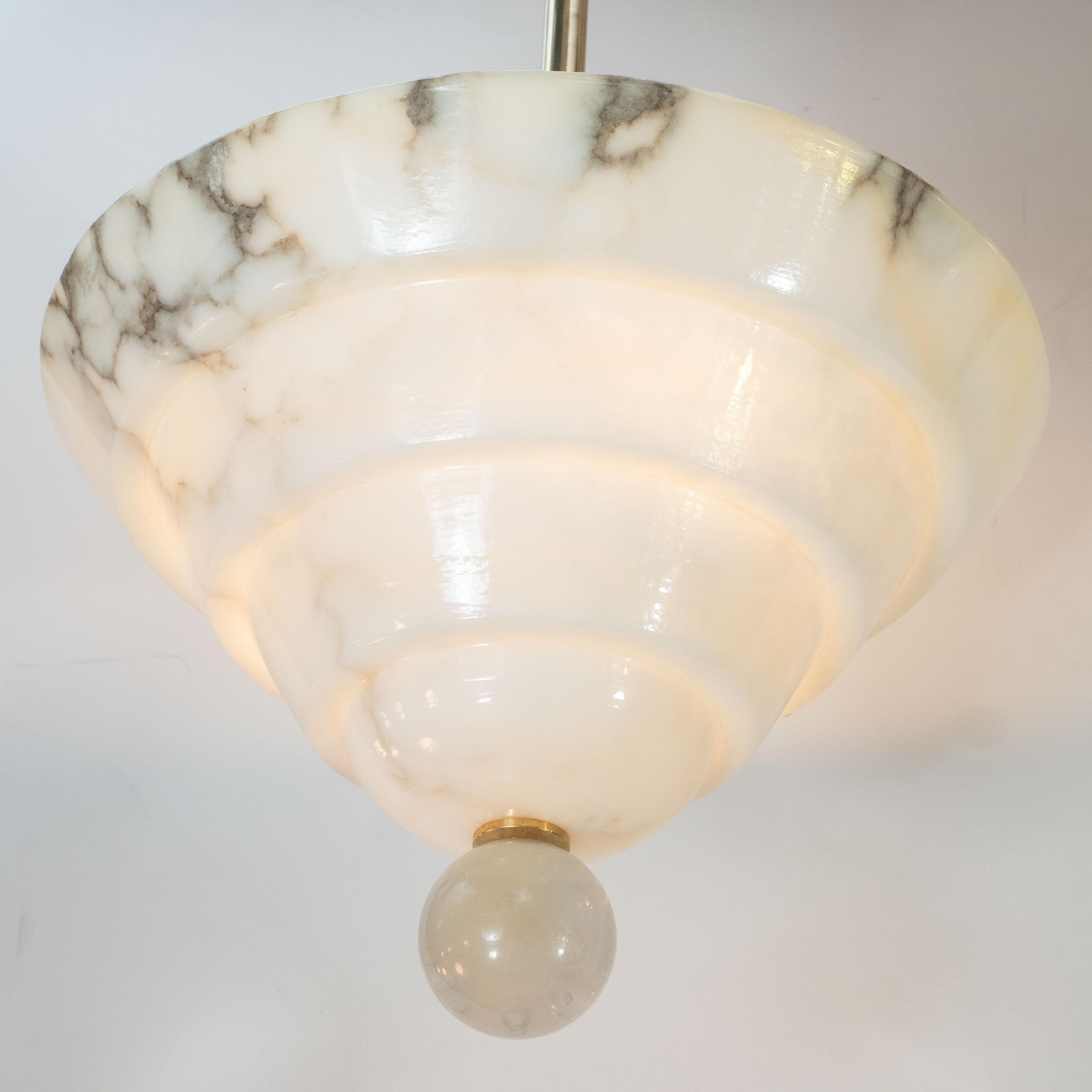 This elegant modernist alabaster chandelier was crafted in the United States. Using a single slab of alabaster, artisans chiseled out the stepped form of the shade, showcasing the rich natural grisaille grain of the stone. The shade is secured with