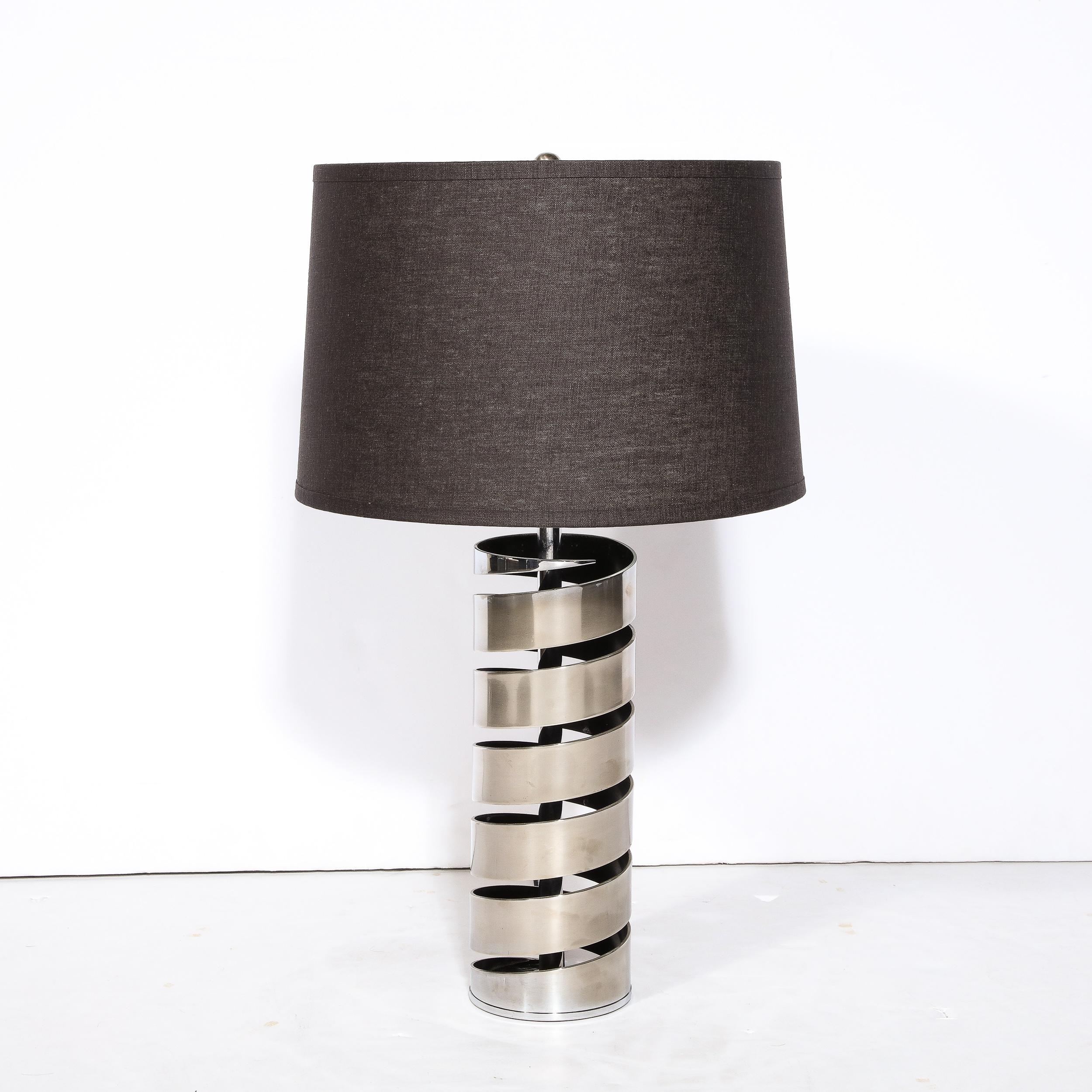This sophisticated modernist spiral form table lamp was realized in the United States during the latter half of the 20th century. It features a torqued spiral form executed in satin nickel with a hollow body. The negative space created by the