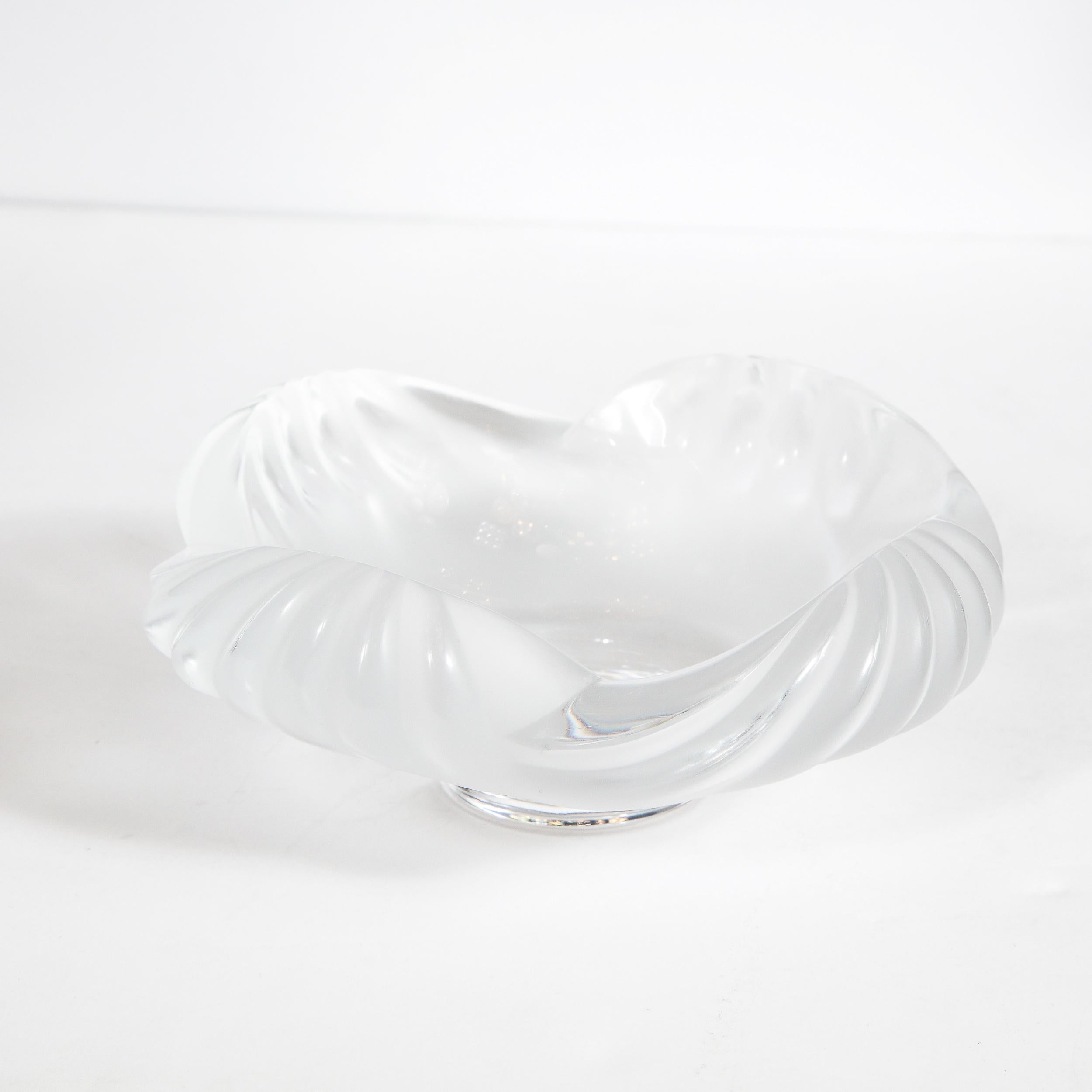 This elegant modernist bowl was realized in France by Lalique- one of France's finest luxury glass and jewelry houses since 1888. It features a scalloped perimeter with channeled sides- suggesting stylized oceanic waves- in a combination of frosted