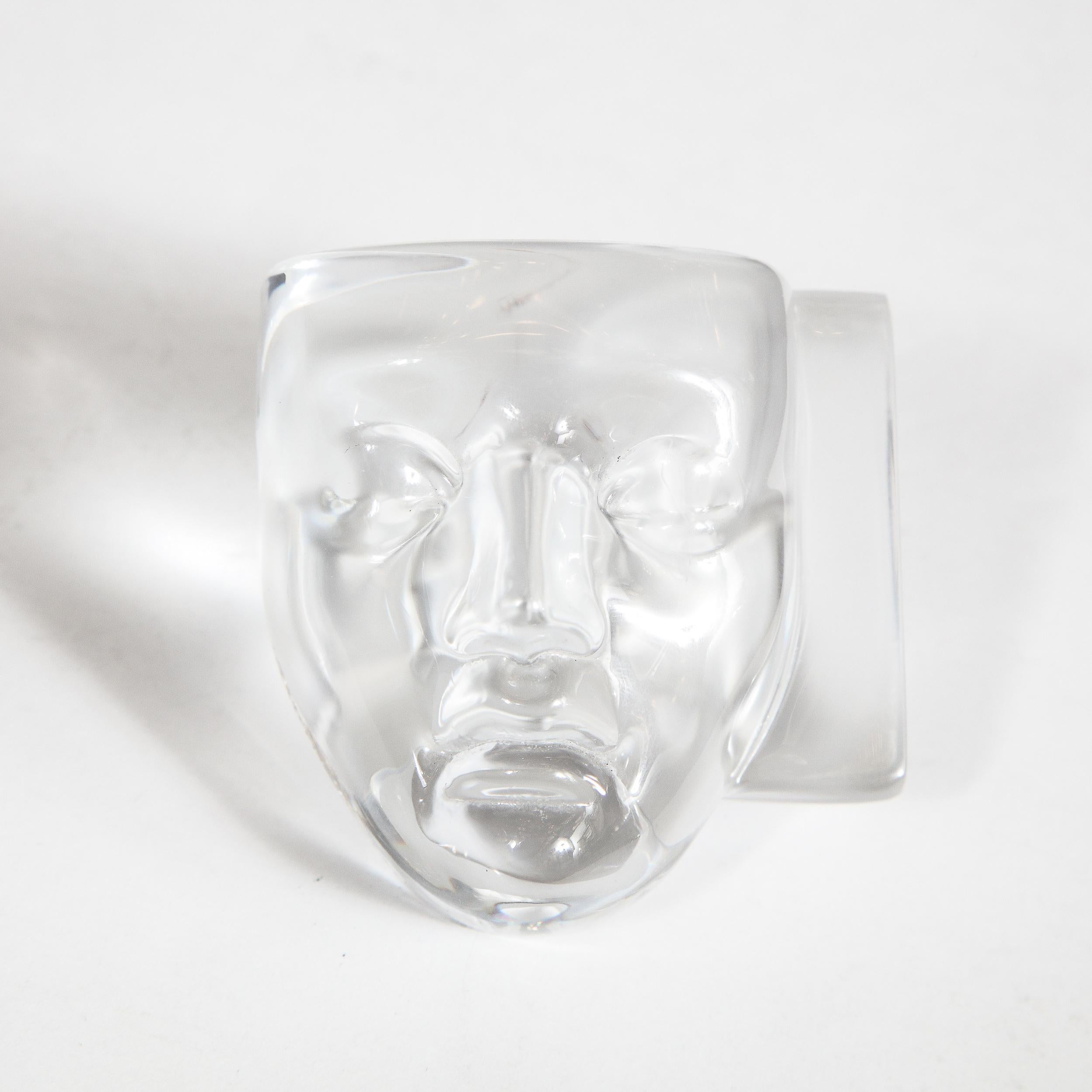 This elegant modernist paperweight was designed by Hilton McConnico and realized by the legendary French maker Daum. It features two Commedia Dell'arte masks (comedy and tragedy) adjoined at a perpendicular angle- one frosted, and the other
