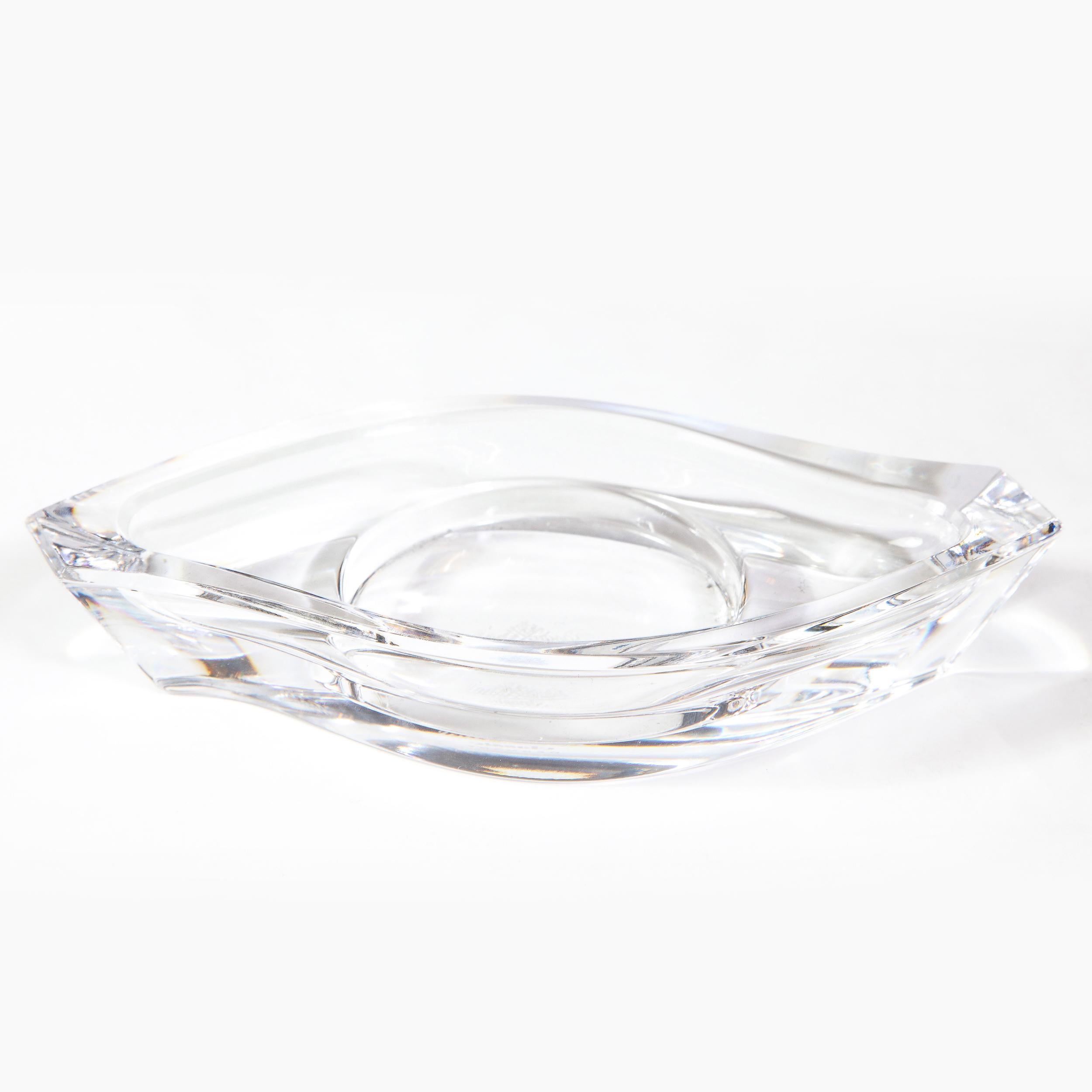 This stunning modernist dish was realized by the esteemed German maker Rosenthal. It offers a sinuously curved ellipsoid form with raised sides and a central circular depression. The form suggests the ancient Egyptian symbol of the Eye of Horus,