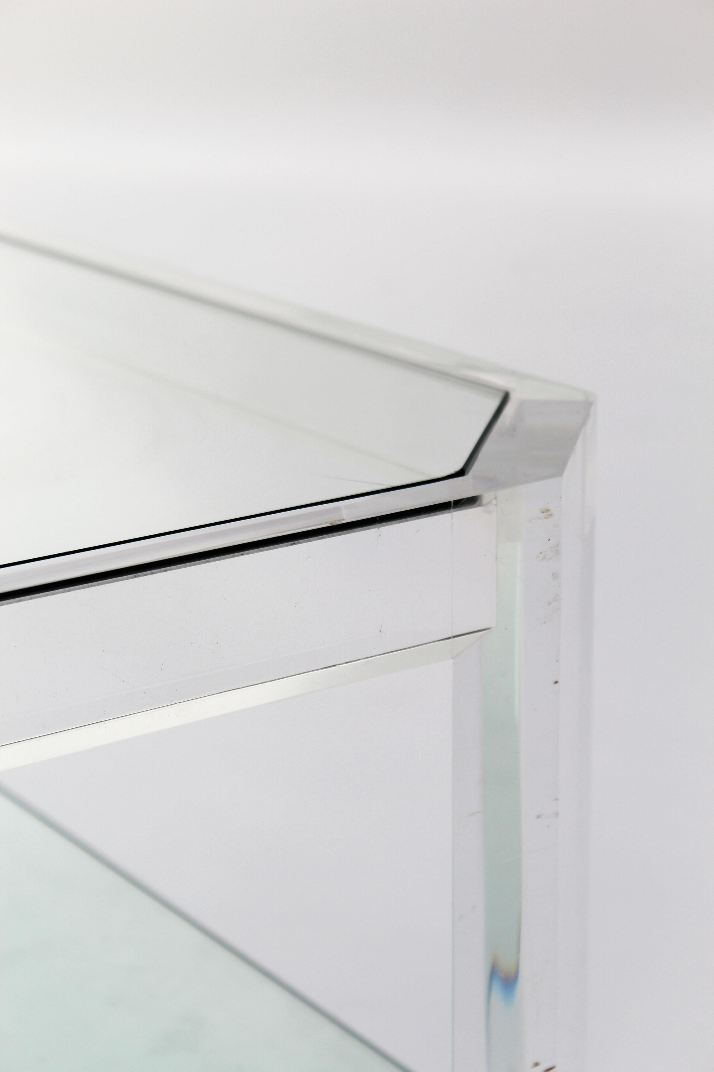Rare table basse rectangulaire attribuée au designer français David Lange, vers les années 1970. Structure en Lucite épaisse, aux coins inclinés, accueillant deux plateaux de verre insérés sur deux niveaux. 

Ce jeu de transparence, de lumière et de