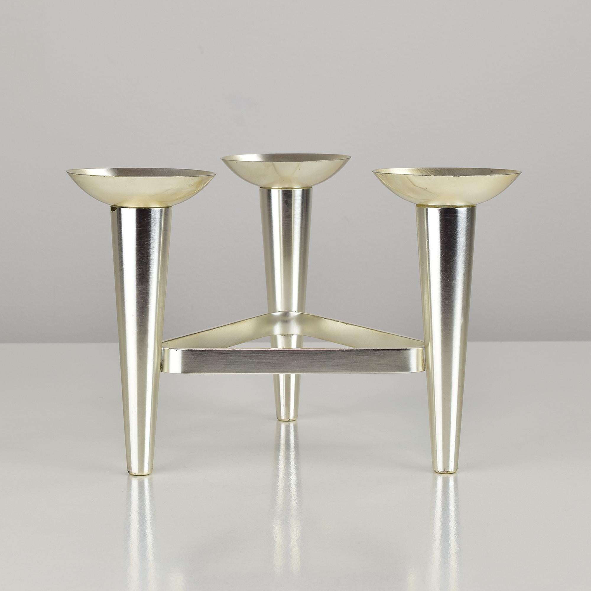 Dieser elegante modernistische Kerzenständer, der in den 1960er Jahren von WMF in Deutschland hergestellt wurde, zeichnet sich durch ein auffälliges geometrisches Design mit drei konischen Kerzenhaltern aus, die in einer dreieckigen Formation