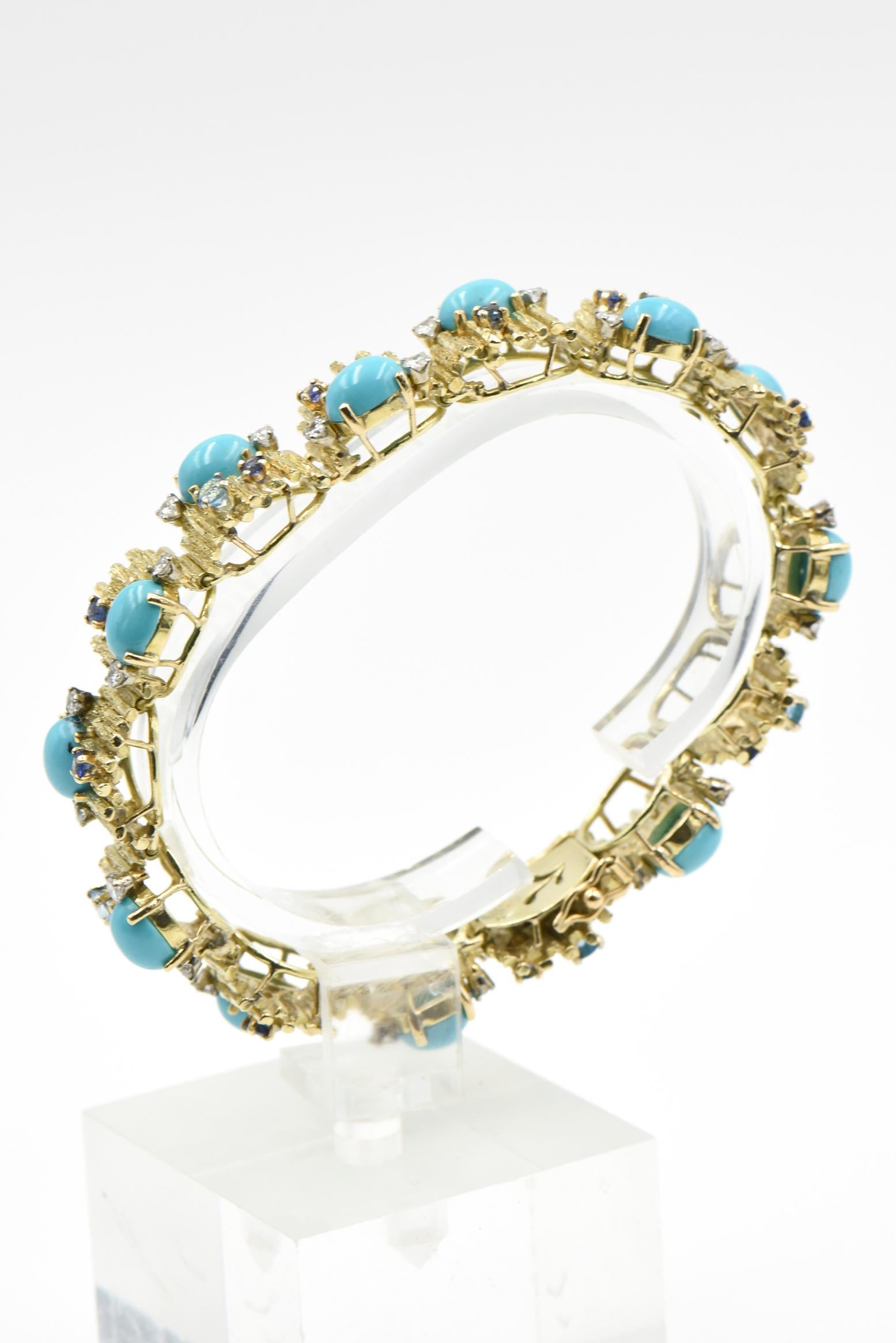 Wonderful 1960's bracelet by Jack Gutschneider features bark finish links accented by cabochon turquoise pieces and facetted sapphires, blue topaz and diamonds mounted in 14k yellow gold.   Bracelet is 7