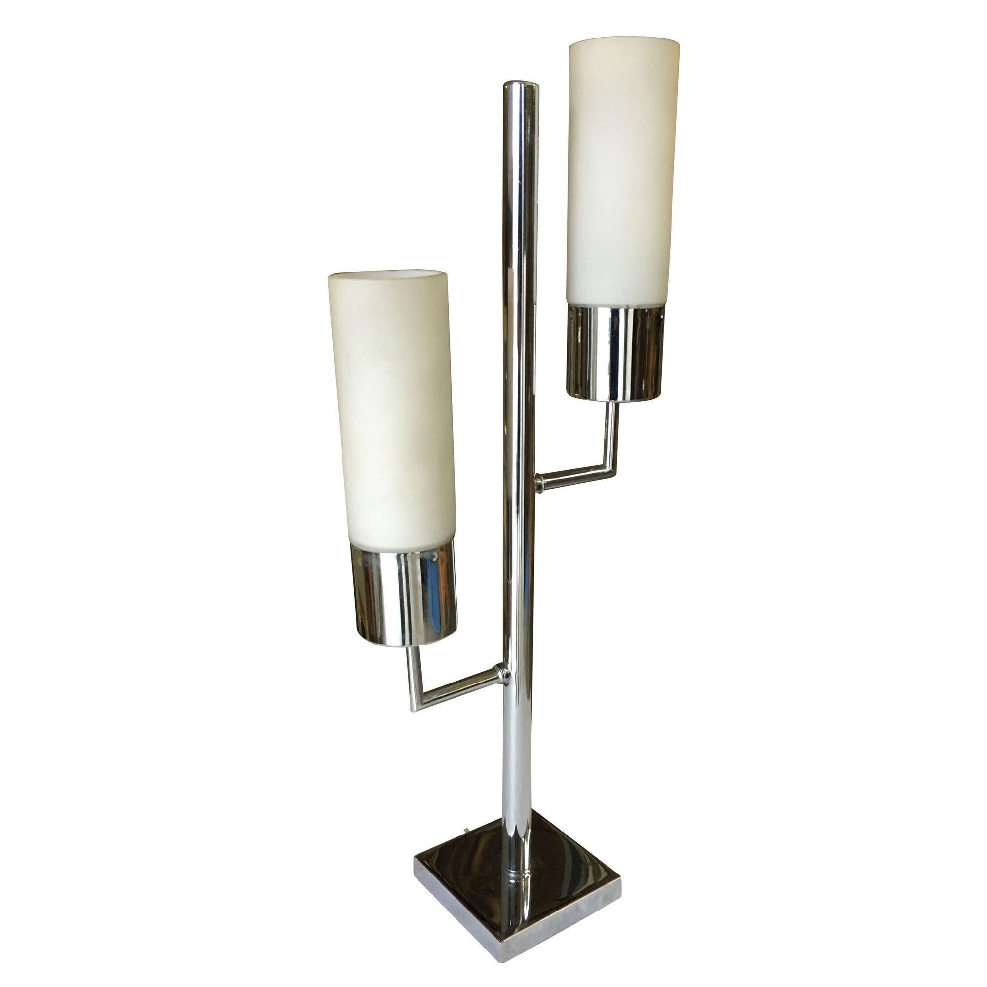 Modernist, midcentury inspired twin cylinder lamp featuring a chrome base and body featuring two 2 lights each with a frosted glass cylinder shade.
