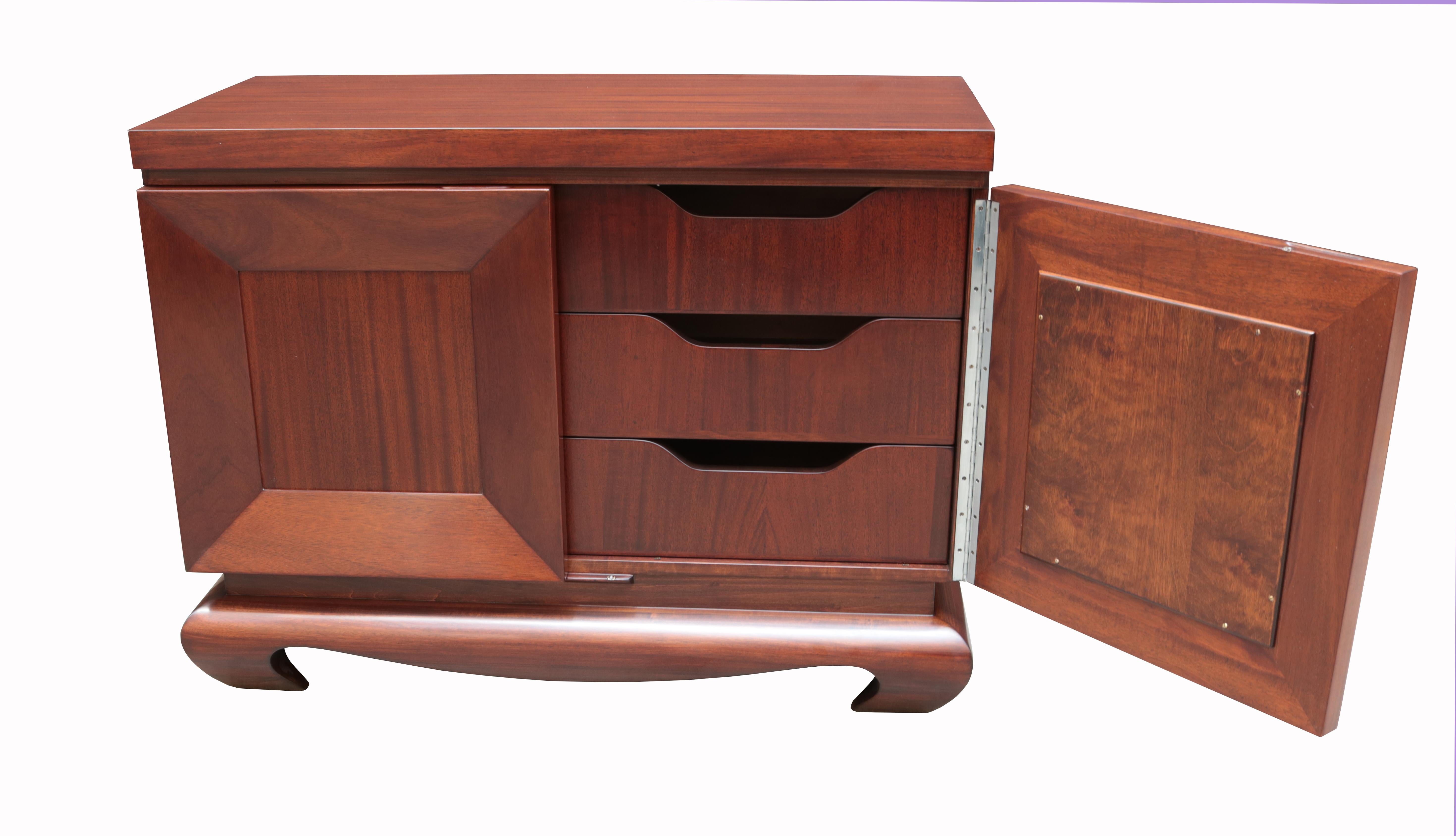 A Modernist two-door cabinet.
Doors with recessed front panels
and three interior drawers,
Asian-inspired sculptural base,
featuring branded signature 