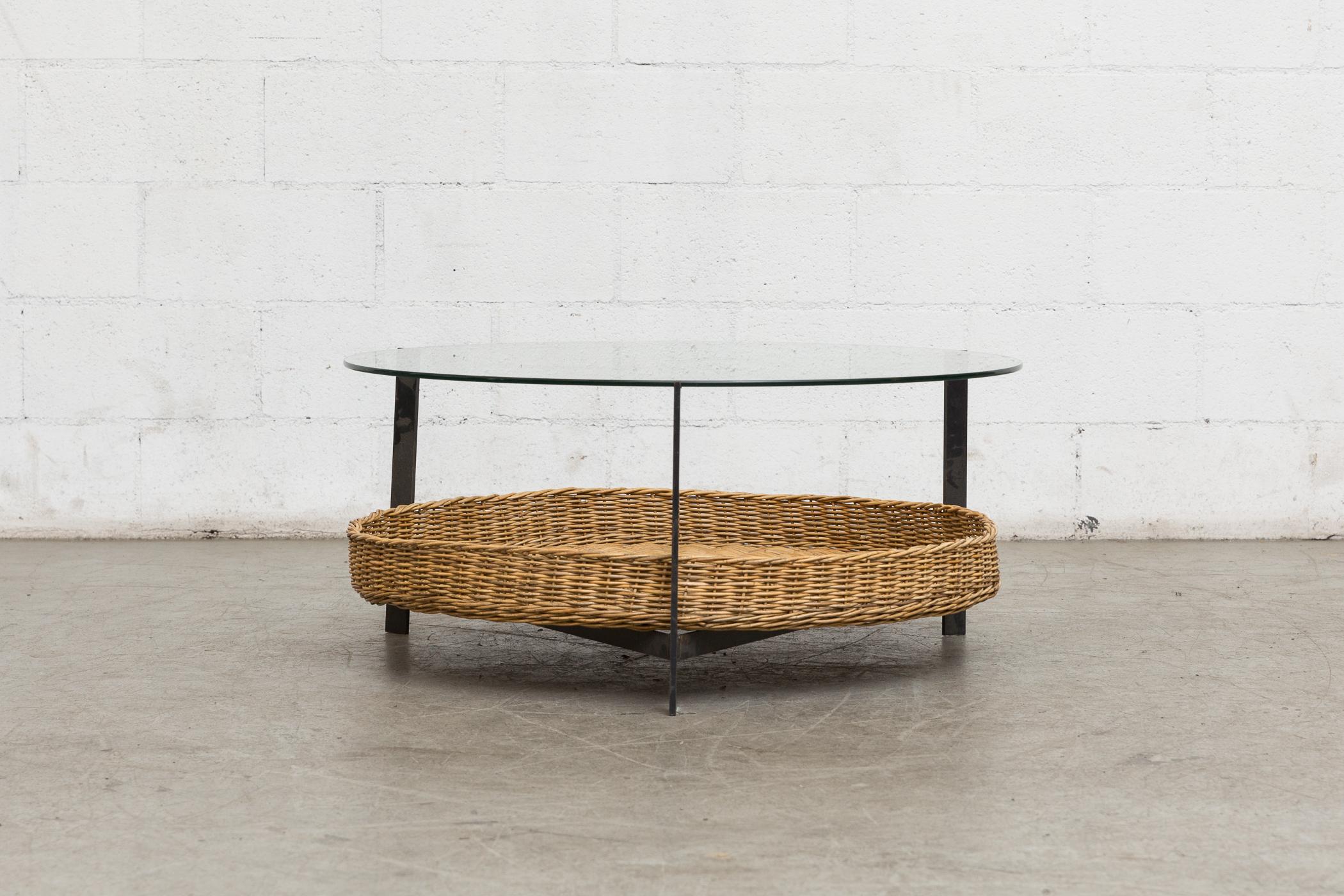 Midcentury Round Glass Coffee Table. with Woven Wicker Lower Basket Black Enameled Metal Frame with Clear Plate Glass. Original Condition with Visible Wear Consistent with its age and usage. Other Round and Square Tables available and listed