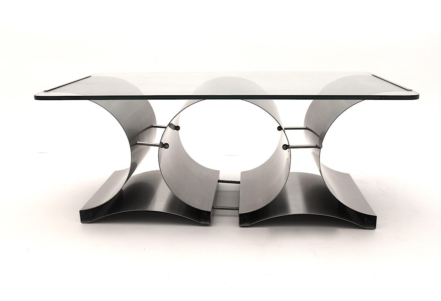 Table basse ou table de canapé vintage moderniste en acier inoxydable et verre transparent conçue par Francois Monnet vers 1970 en France.
Une belle table basse avec une base structurée en métal et surmontée d'un verre transparent épais et