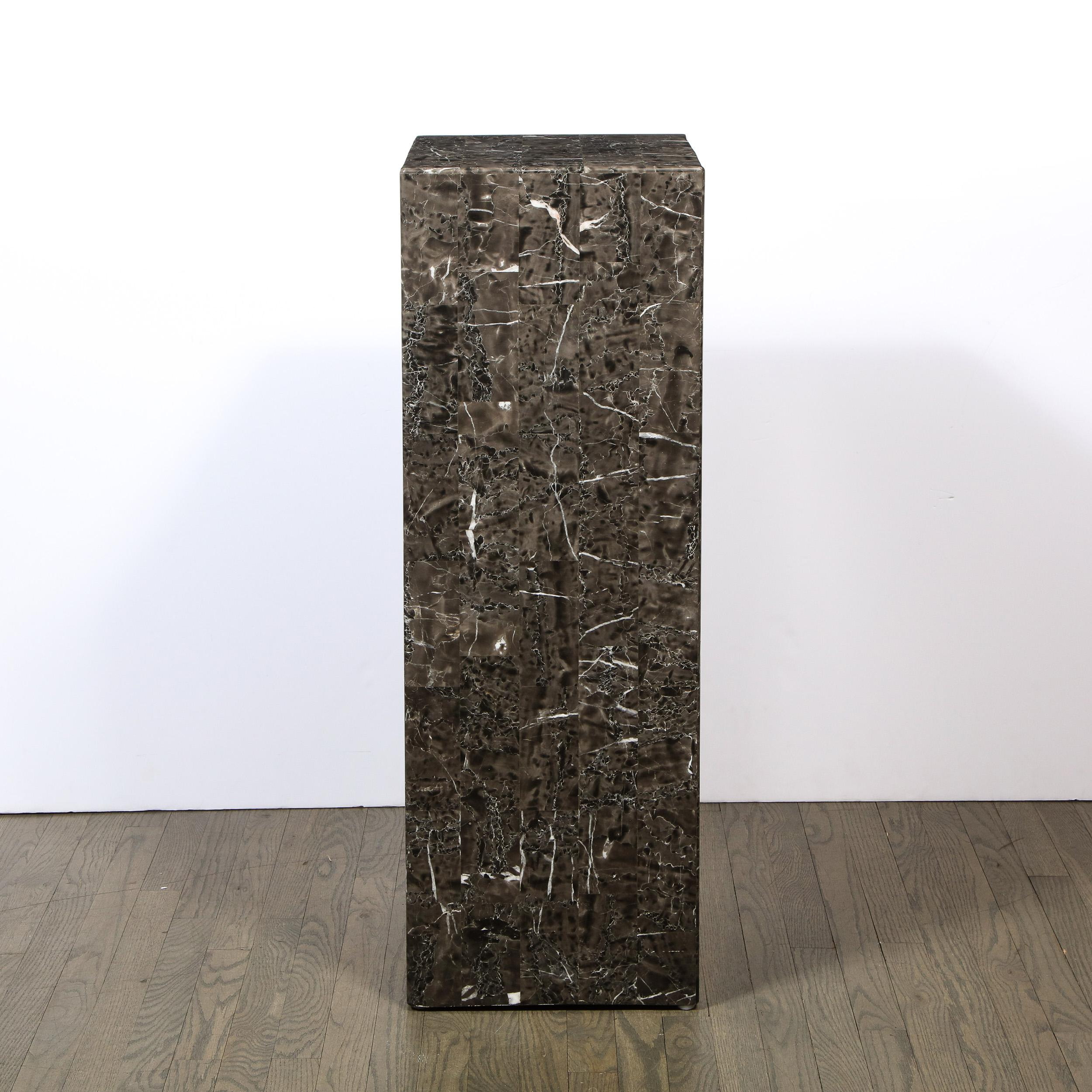 This refined modernist pedestal was realized in the United States during the latter half of the 20th century. It features a volumetric rectangular body with a tessellated marble exterior, showcasing the dynamic and stunning inherent stone grain.
