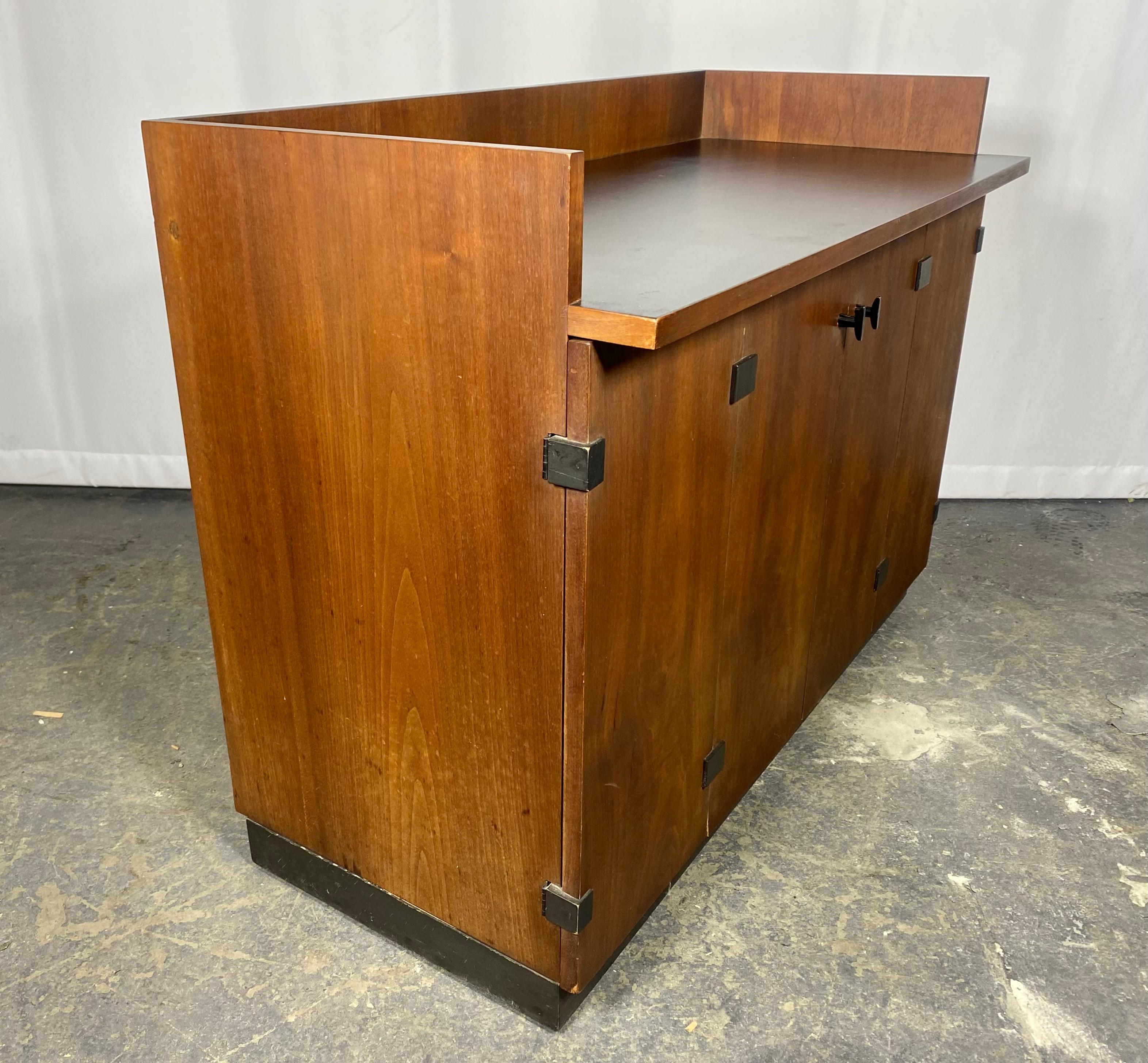 This walnut bar cabinet was manufactured by Directional in the 1960s and attributed to both Milo Baughman and Kipp Stewart due to stylistic attributes associated with both designers, but lack of source material to support. Most commonly credited to