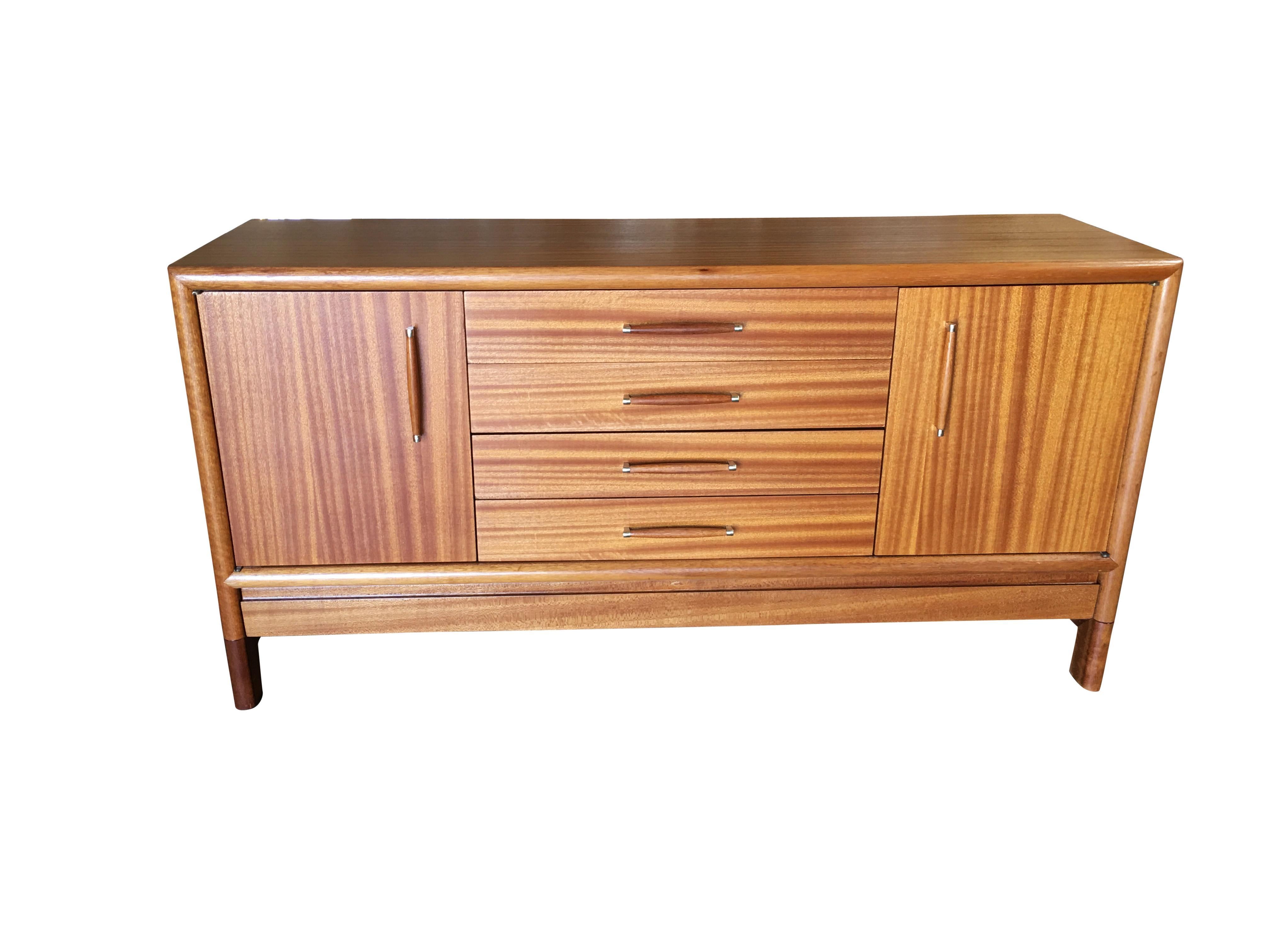 Modernist walnut buffet/credenza by John Keal for Brown Saltman. The buffet features two single door cubby spaces on each side of a four-drawer cluster all with custom made brass and walnut handles. Special to this piece is a secret hidden cabinet