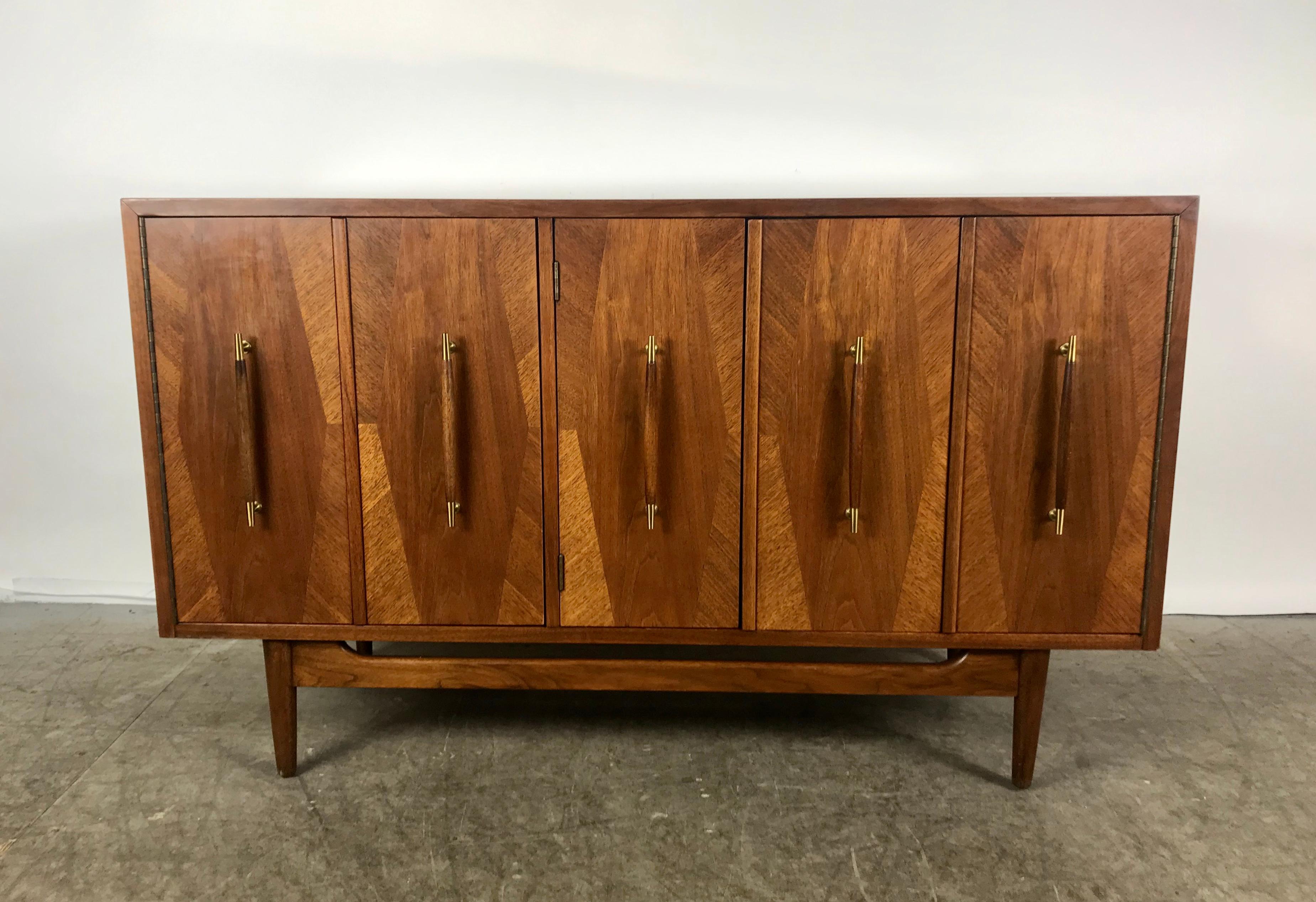 Stunning modernist walnut cabinet or server. Dramatic wood veneers, walnut and brass hand pulls. American of Martinsville, Designed by Merton Gershun from the 'Dania
