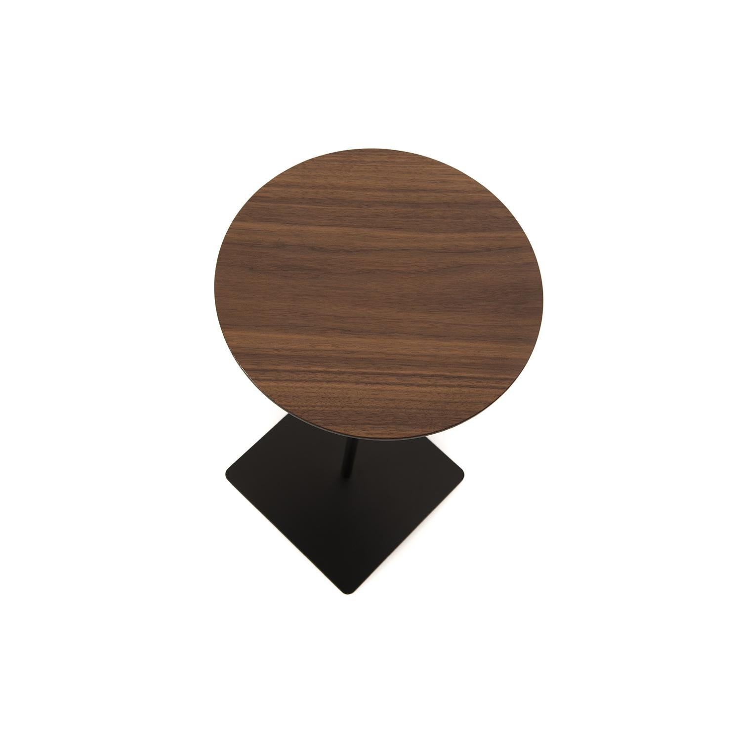 This round top walnut table sits upon a slender, black stem with a square base.