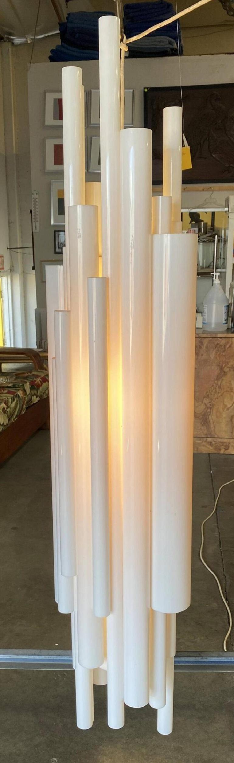 Made in the USA, this gorgeous lucite tube chandelier features a brass hanger with several layers of asymmetric lucite tubes. The light glistens through the white Lucite tubes, which are uniform in shape and size.

Transport your space back to the