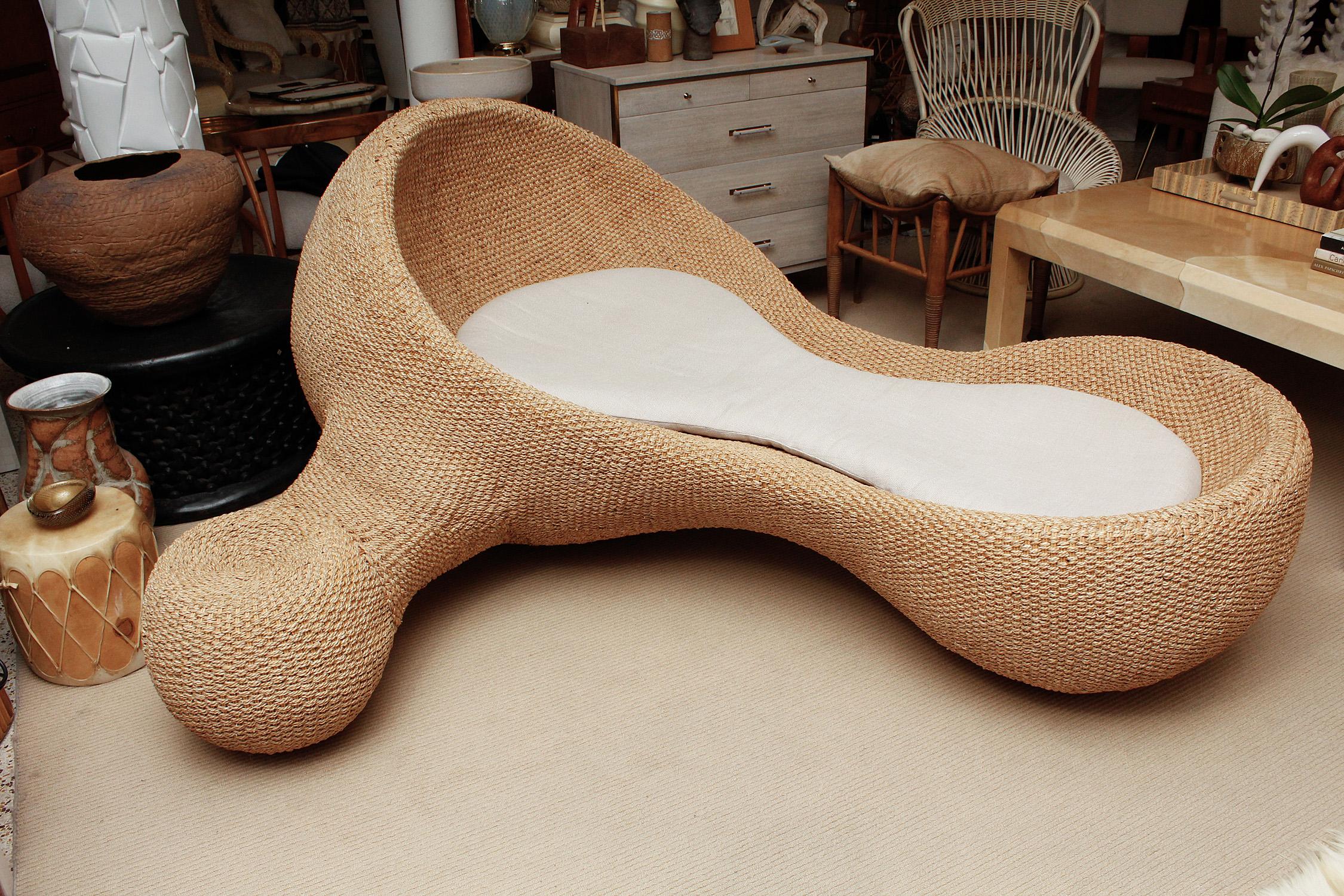 A modernist mix of futuristic form and natural materials inform the design of this generously scaled chaise longue, crafted from wicker and woven sea grass rope on a metal frame. Maker unknown. Original cushion with newer upholstery. Not recommended