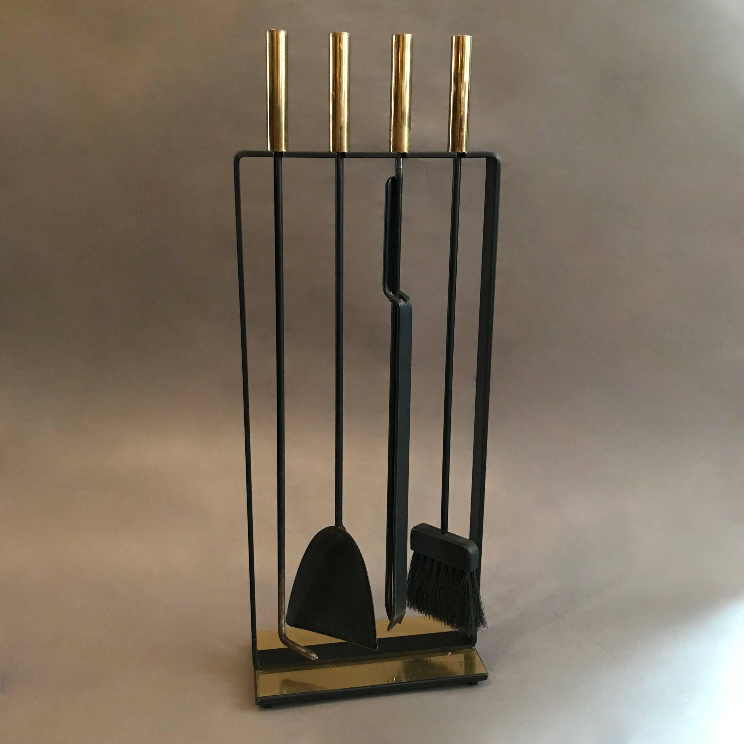 Modernist, four-piece, fireplace tool set by Pilgrim attributed to George Nelson features black wrought iron frame and tools with polished brass handles and base.