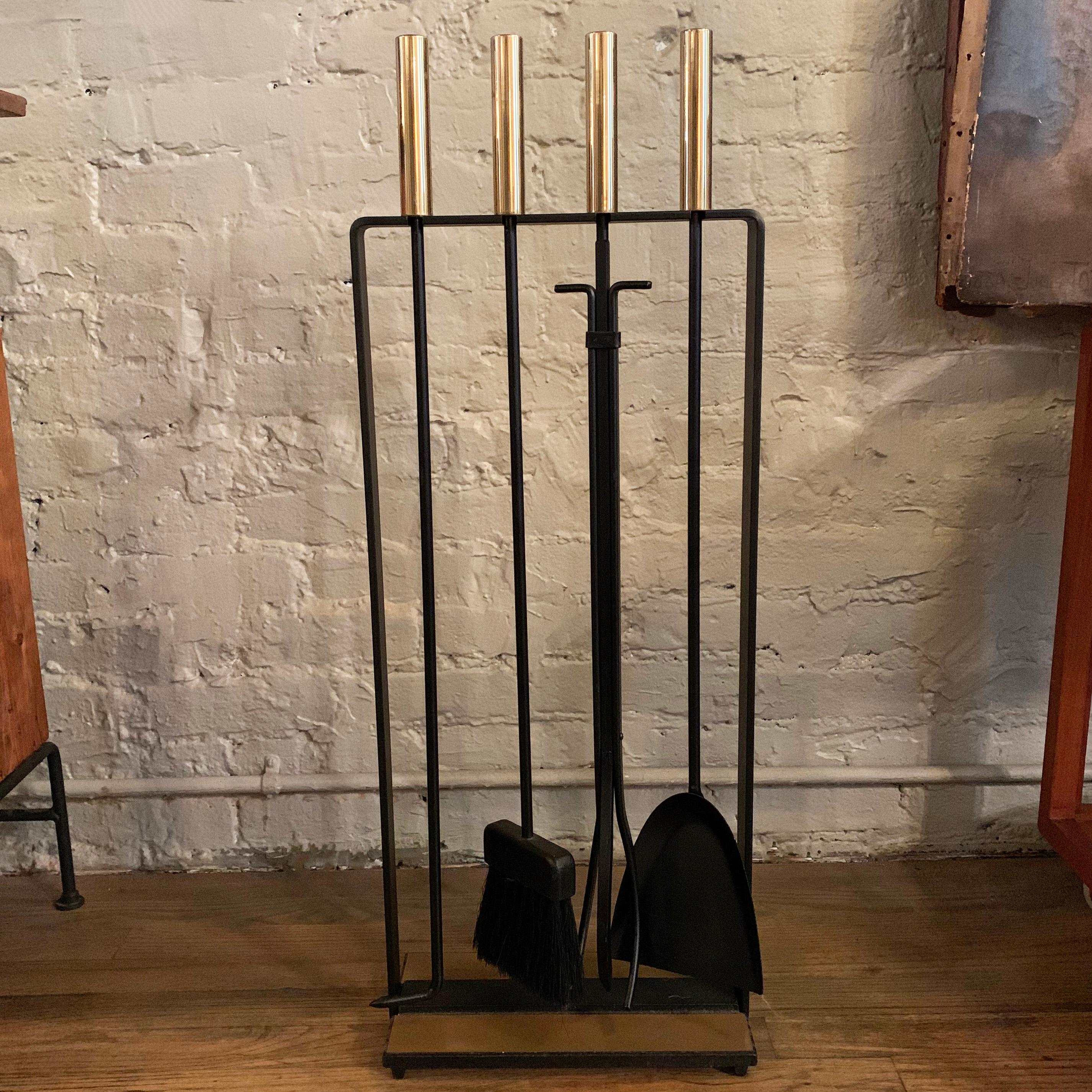Modernist, four-piece, fireplace tool set by Pilgrim attributed to George Nelson features a black wrought iron frame and tools with polished brass handles and matte brass base.
