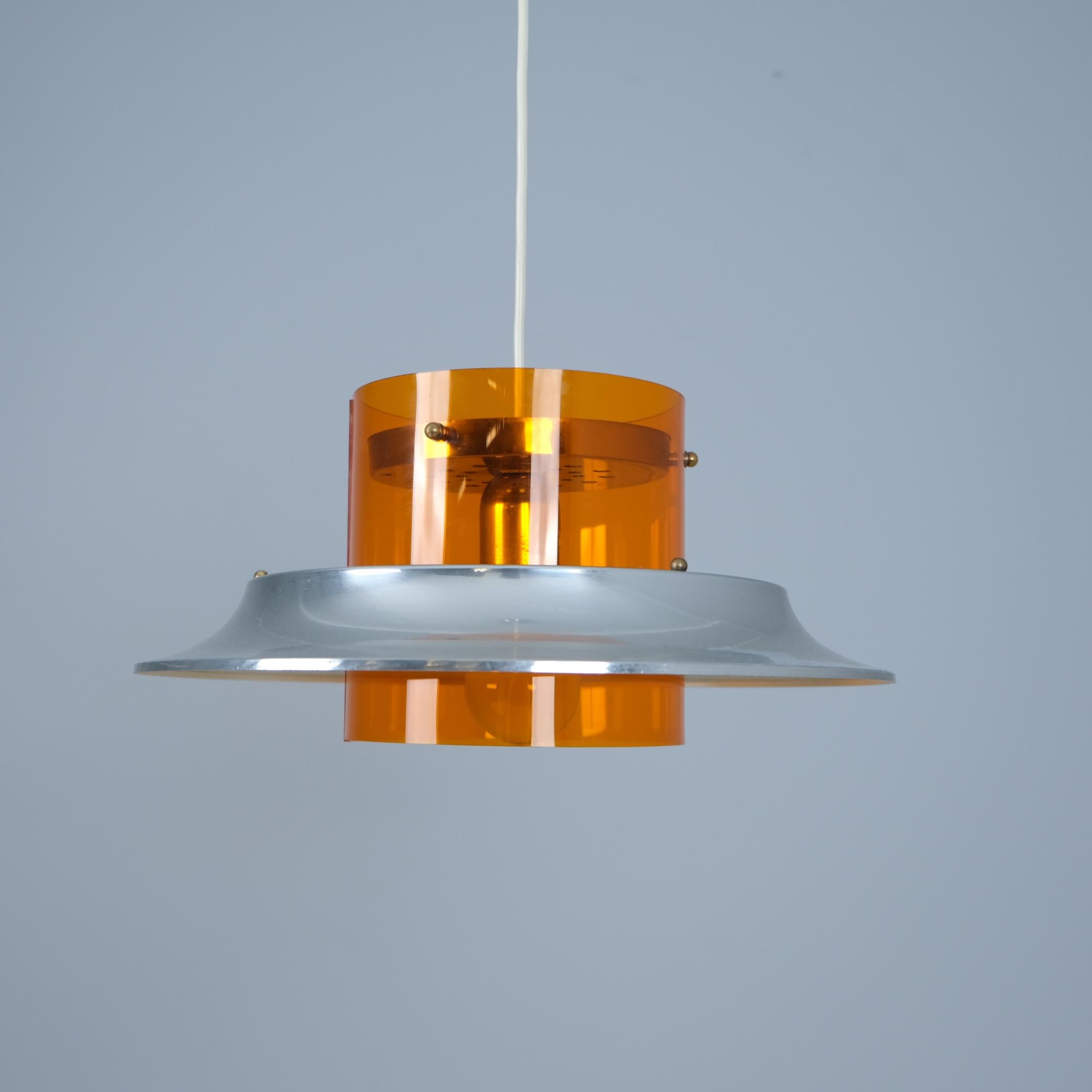 Un sorprendente pendente da soffitto modernista e colorato del designer finlandese Kai Kai (Finnmark), caratterizzato da un cilindro acrilico arancione e da una lamella di alluminio come diffusore di luce. Questo pezzo futuristico incarna il fascino